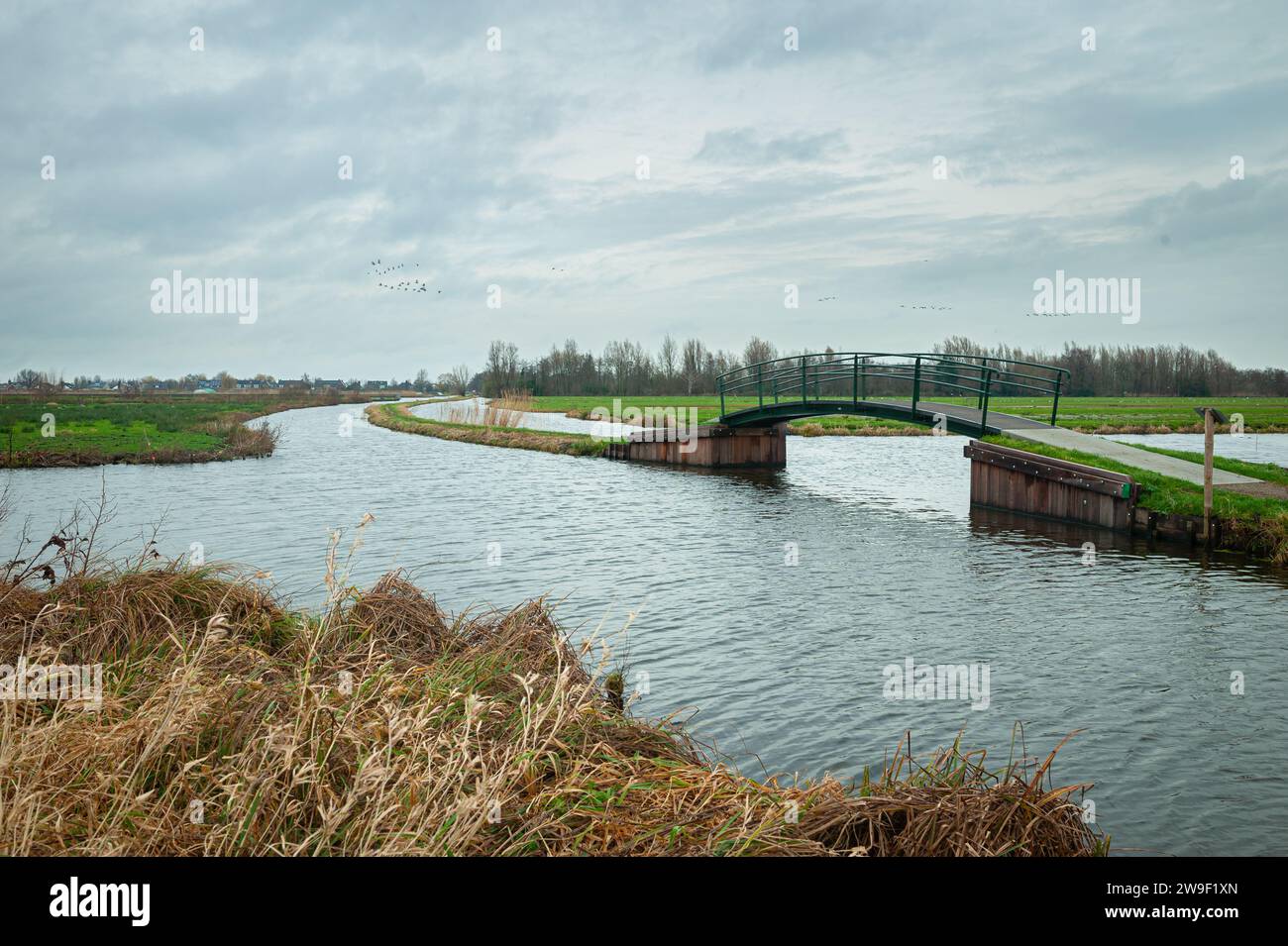 Wanderbrücke über einen der vielen Gräben in der niederländischen Landschaft im Polder Bloemendaal zwischen Gouda und Waddinxveen, Niederlande. Stockfoto