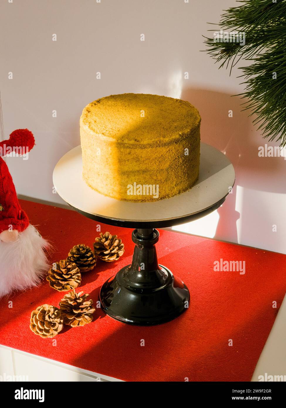 Ein festlicher roter Santa-Claude-Hut sitzt auf einem Honigkuchen auf einem Tisch und verleiht der Kulisse einen gewissen Weihnachtsstimmung Stockfoto
