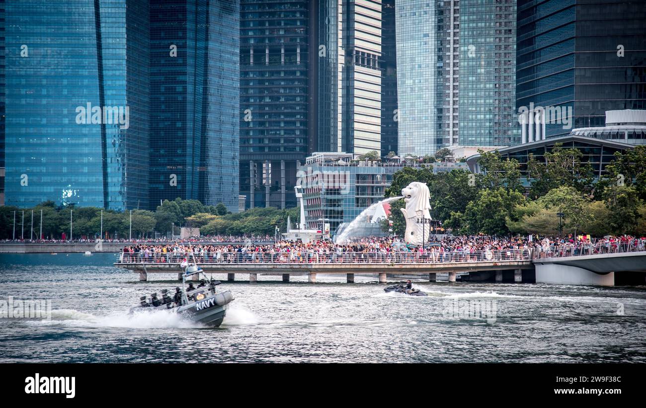 Eine Gruppe von Menschen, die an einem sonnigen Tag eine gemütliche Bootsfahrt bei einer besonderen Veranstaltung genießen: Merlion Park und CBD Urban Architecture, Marina Bay, Singapur Stockfoto