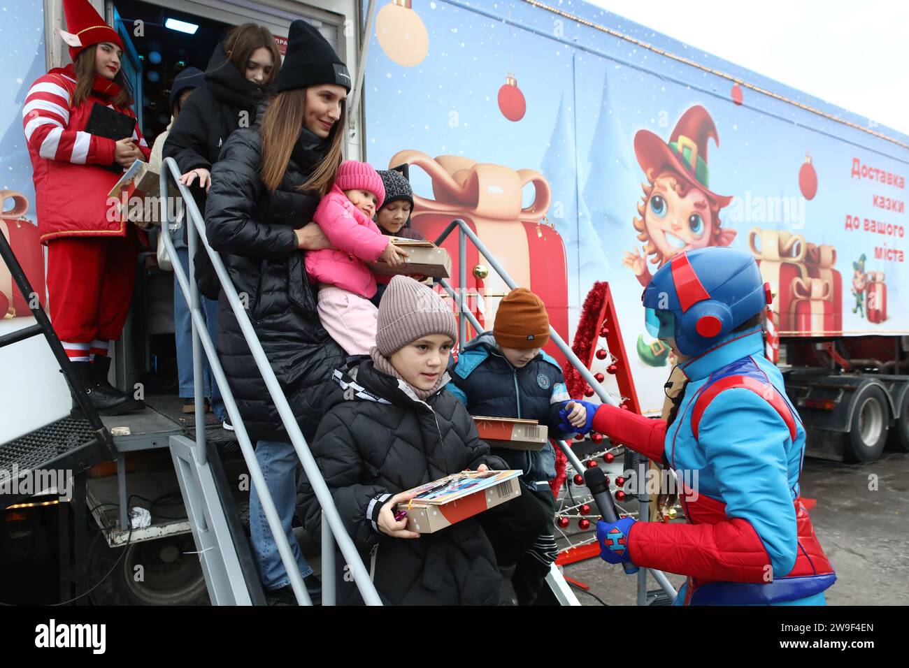 Nicht exklusiv: CHERVONOHRAD, UKRAINE - 25. DEZEMBER 2023 - Kinder hinterlassen auf einer Weihnachtsmesse einen festlichen Trailer der Nova Poshta mit Geschenken Stockfoto