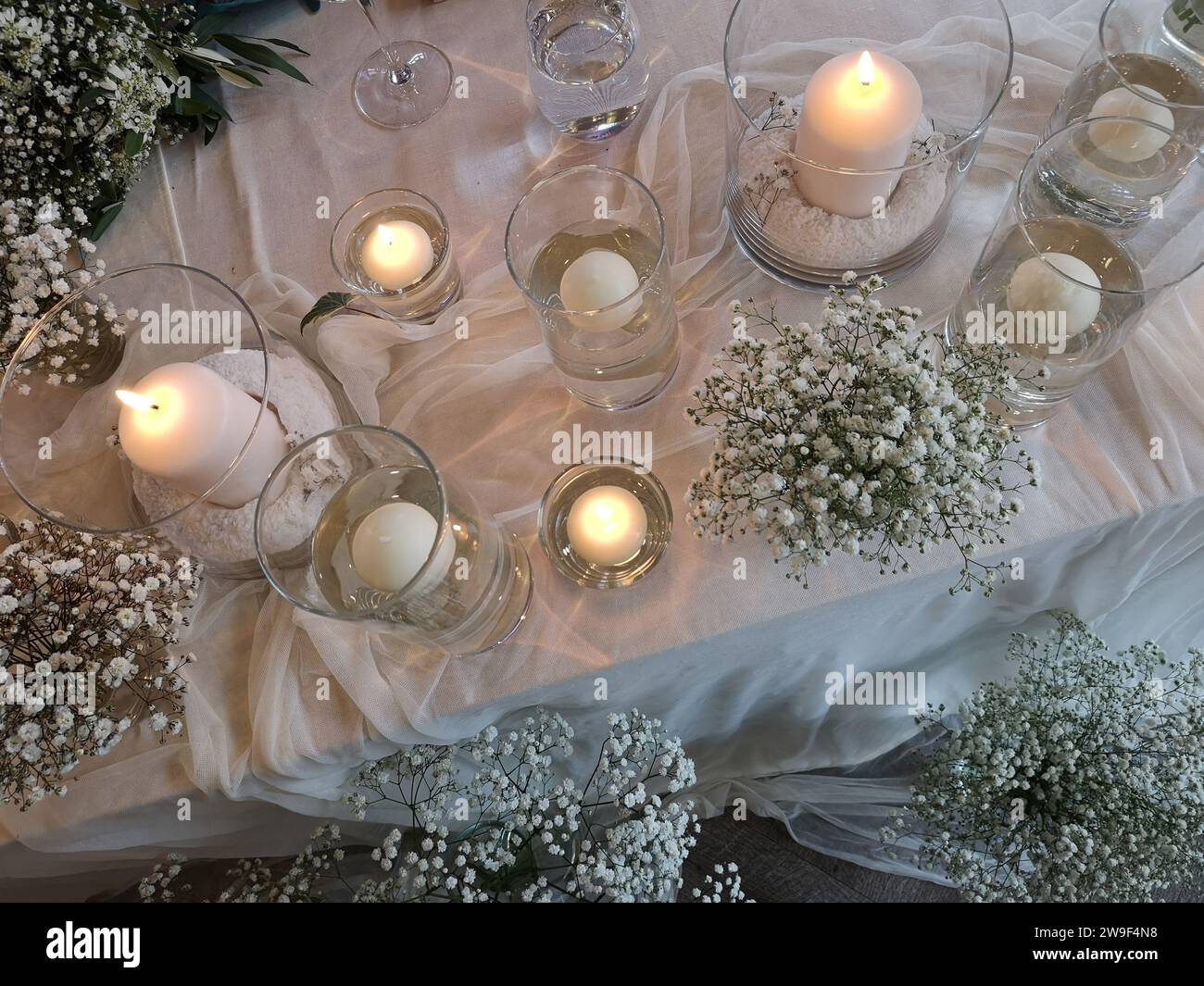 Ein kunstvoll gestalteter Stillleben-Tisch mit weißen Blumen und Kerzen Stockfoto