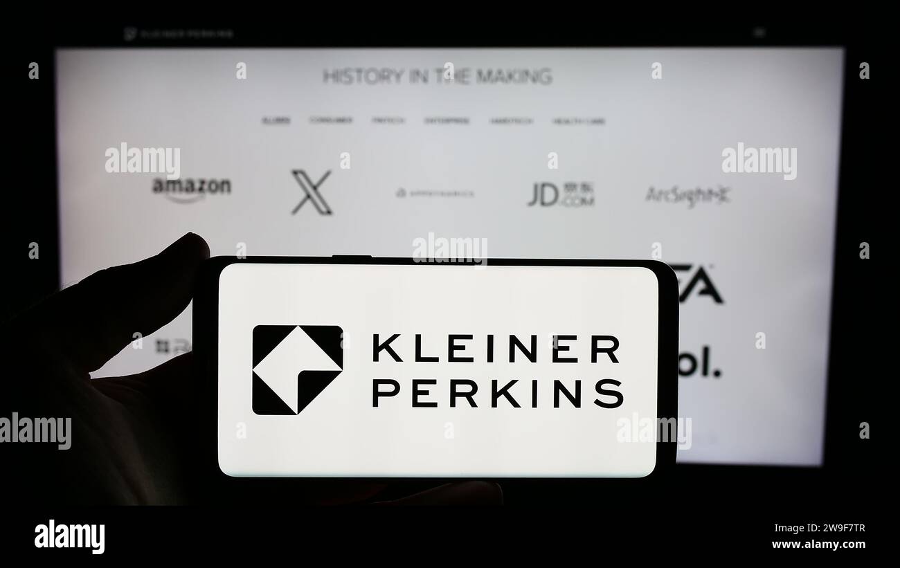 Person mit Smartphone und Logo der US-amerikanischen Risikokapitalgesellschaft kleiner Perkins vor der Website. Schwerpunkt auf dem Display des Telefons. Stockfoto