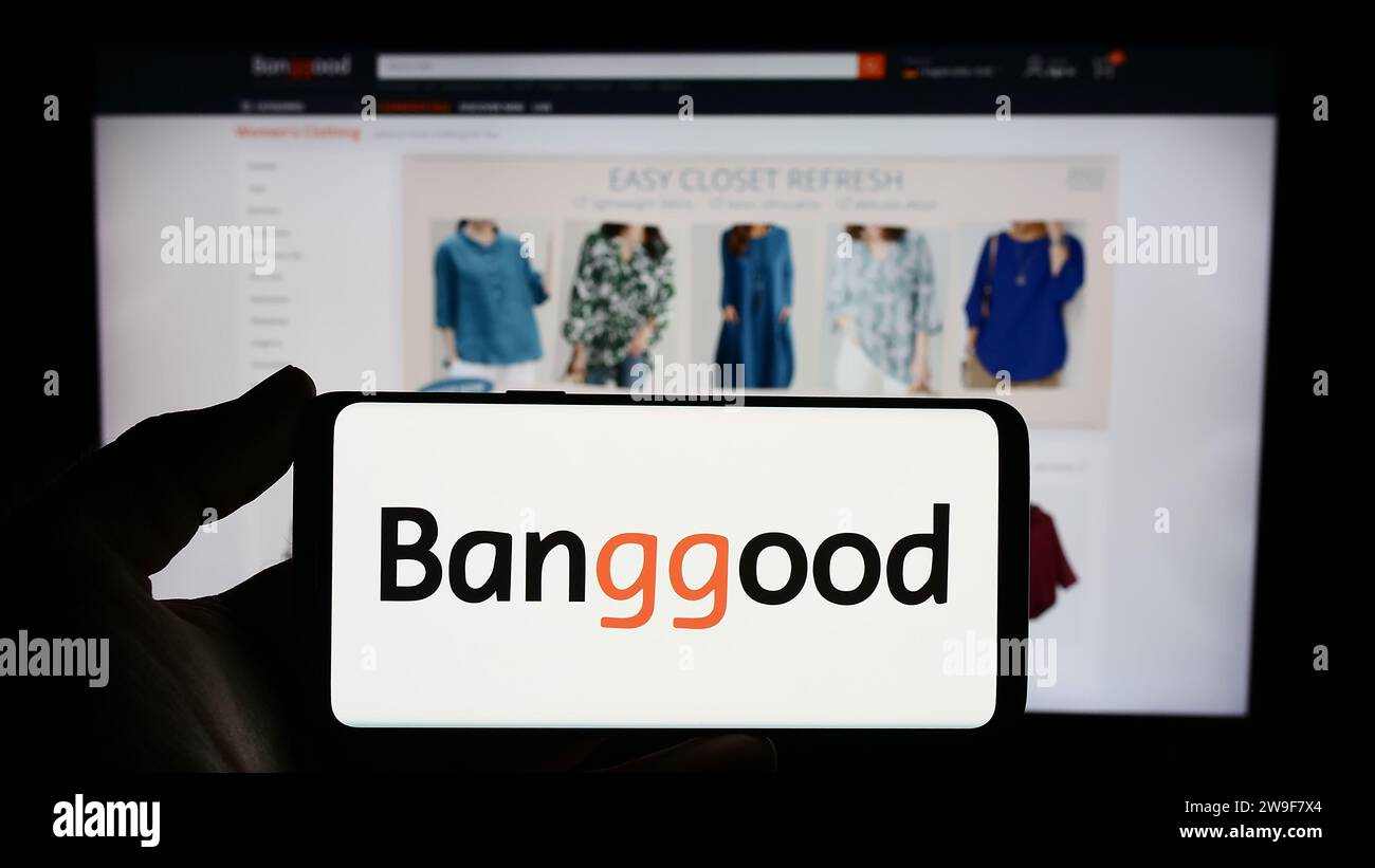 Person mit Smartphone und Logo des chinesischen E-Commerce-Unternehmens Banggood Wholesale vor der Website. Schwerpunkt auf dem Display des Telefons. Stockfoto