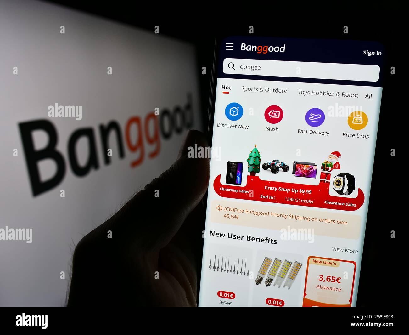 Person mit Smartphone und Webseite des chinesischen E-Commerce-Unternehmens Banggood Wholesale vor dem Logo. Konzentrieren Sie sich auf die Mitte des Telefondisplays. Stockfoto