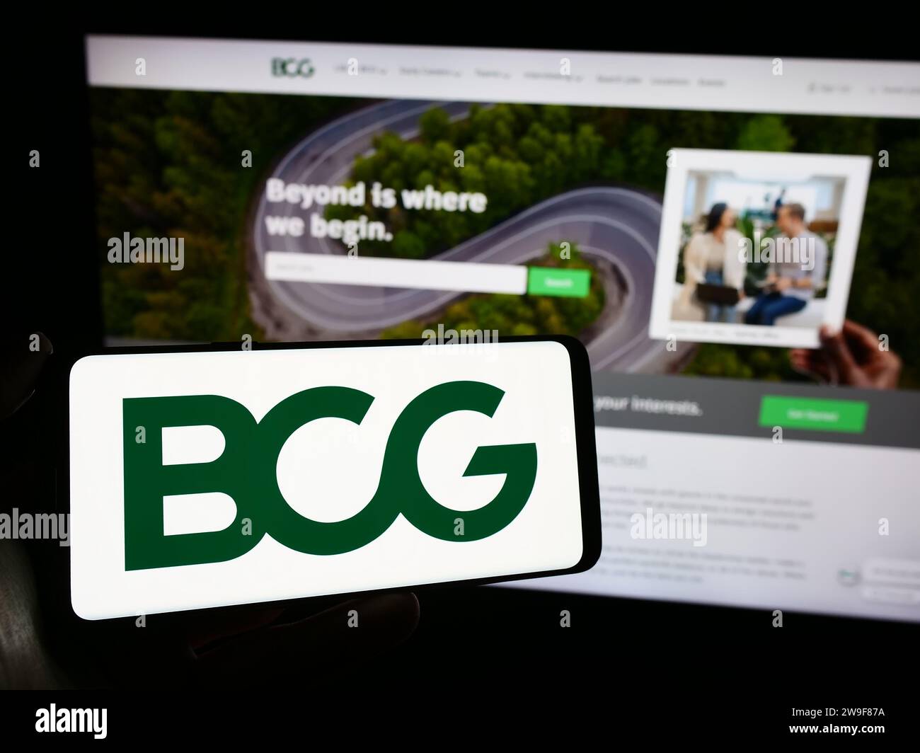 Person, die ein Mobiltelefon mit dem Logo der amerikanischen Firma Boston Consulting Group Inc. Hält (BCG) vor der Webseite. Schwerpunkt auf dem Display des Telefons. Stockfoto