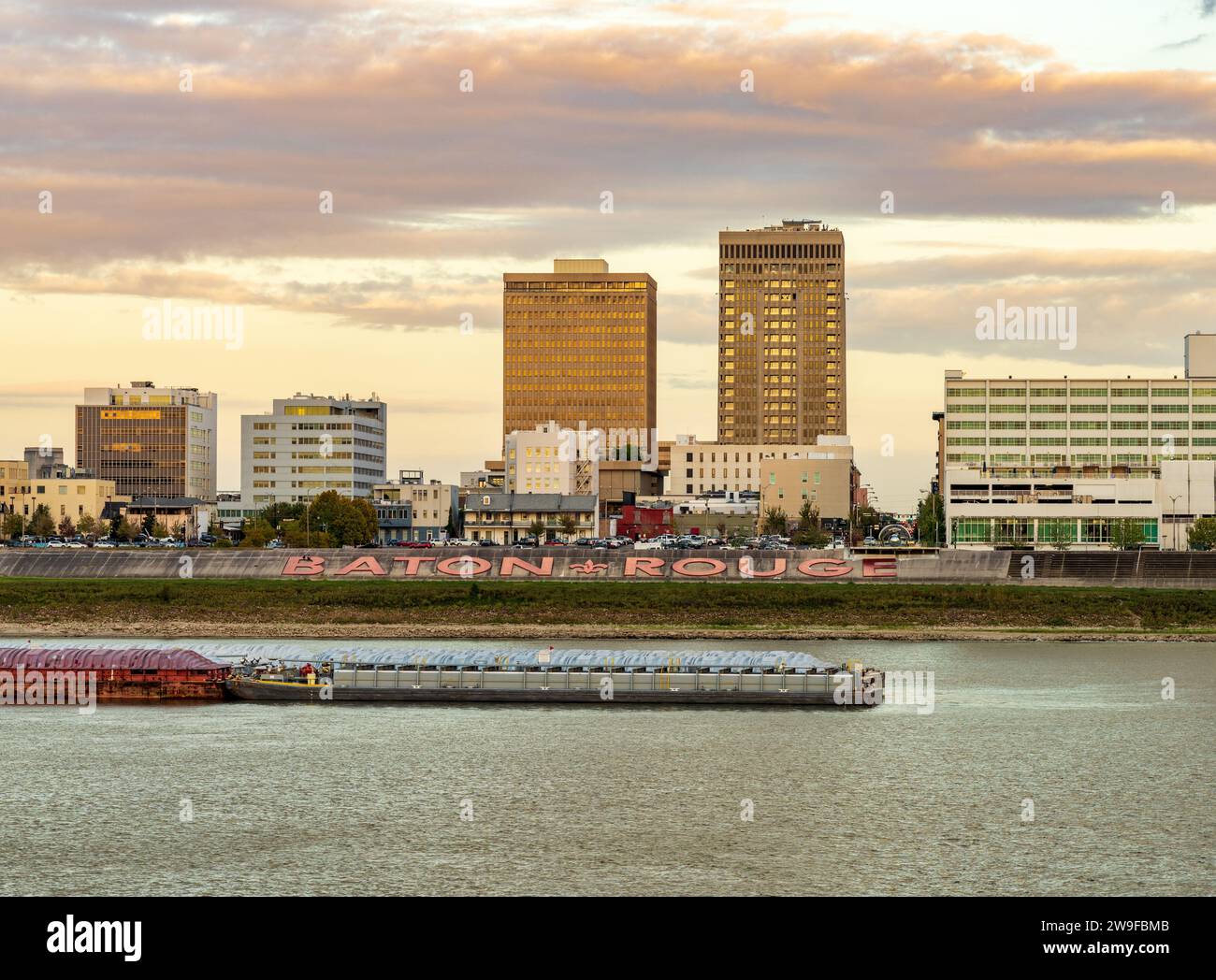 Sonnenuntergang über dem Fluss Lastkähne und Boote im Mississippi River bis zur Skyline von Baton Rouge, der Hauptstadt von Louisiana Stockfoto