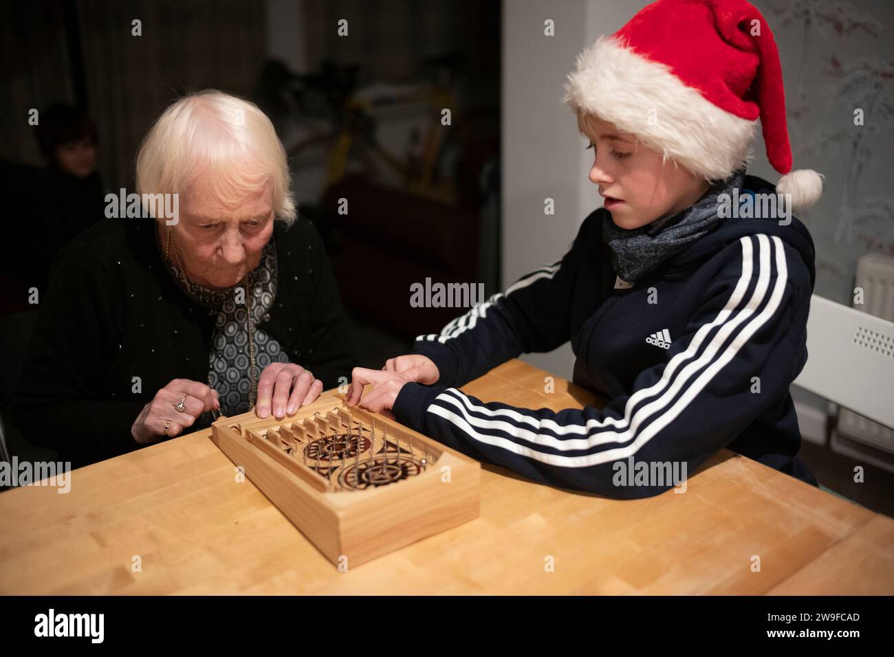 Großmutter und ihr Enkel spielen Tischplatten-Flipperspiel am Weihnachtstag in England, Großbritannien Stockfoto