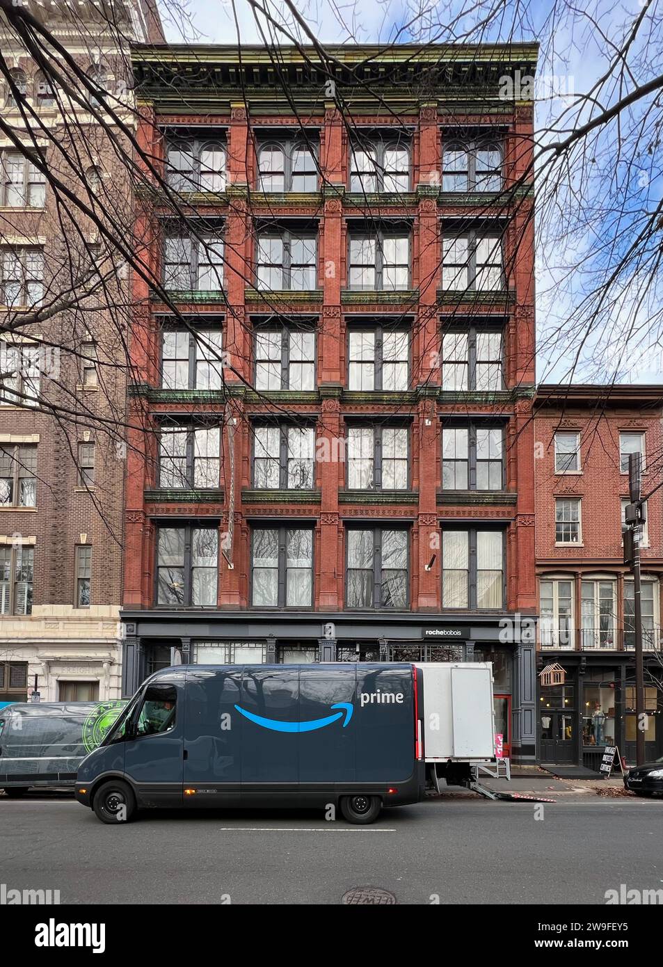 Ein rivianischer Amazon-Lieferwagen parkt entlang der Arch Street, während eine Crew in der Altstadt von Philadelphia Lieferungen tätigt. Stockfoto