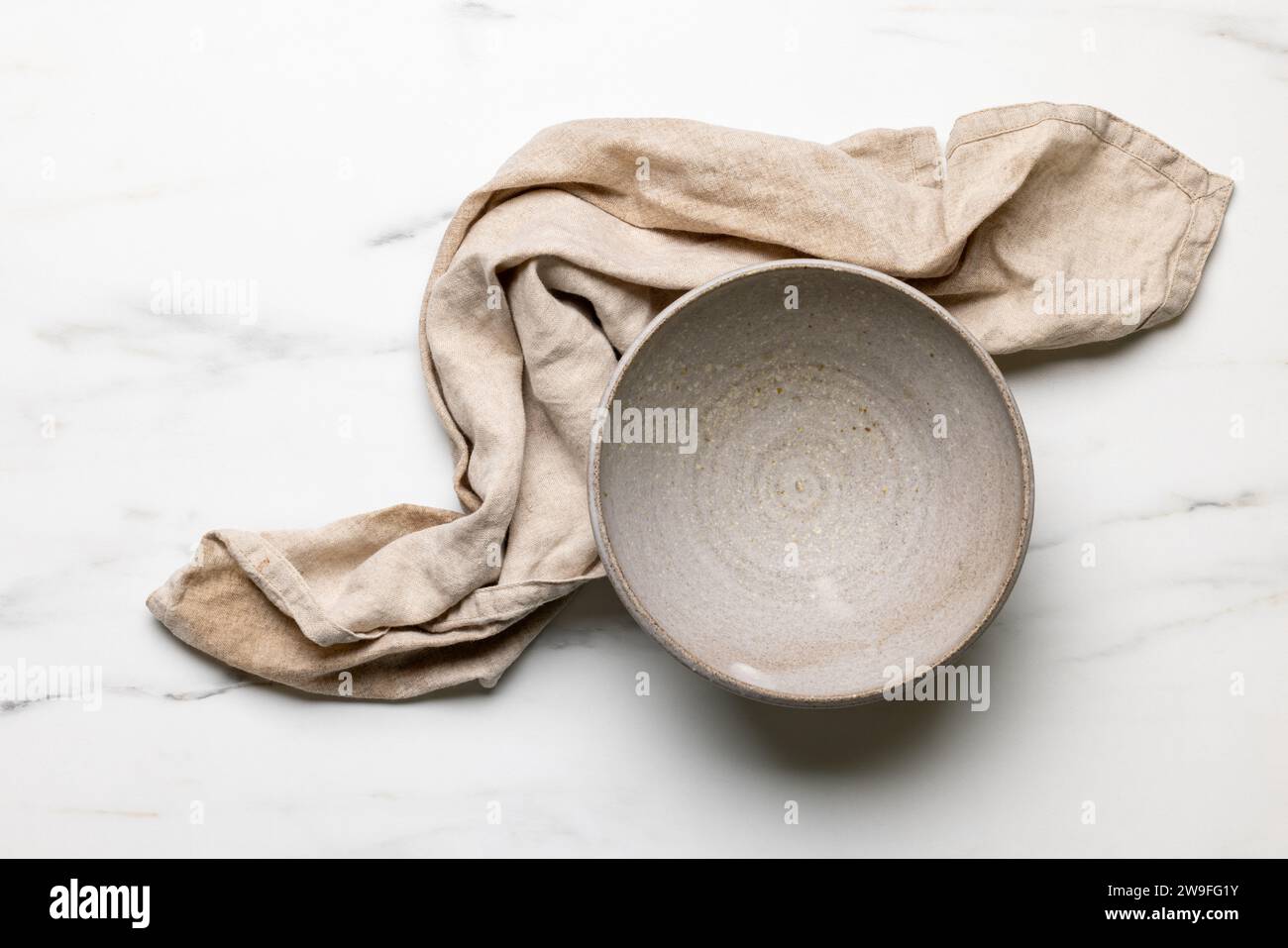 Leere Keramikschale und Leinentuch auf hellem Küchentisch, Blick von oben Stockfoto