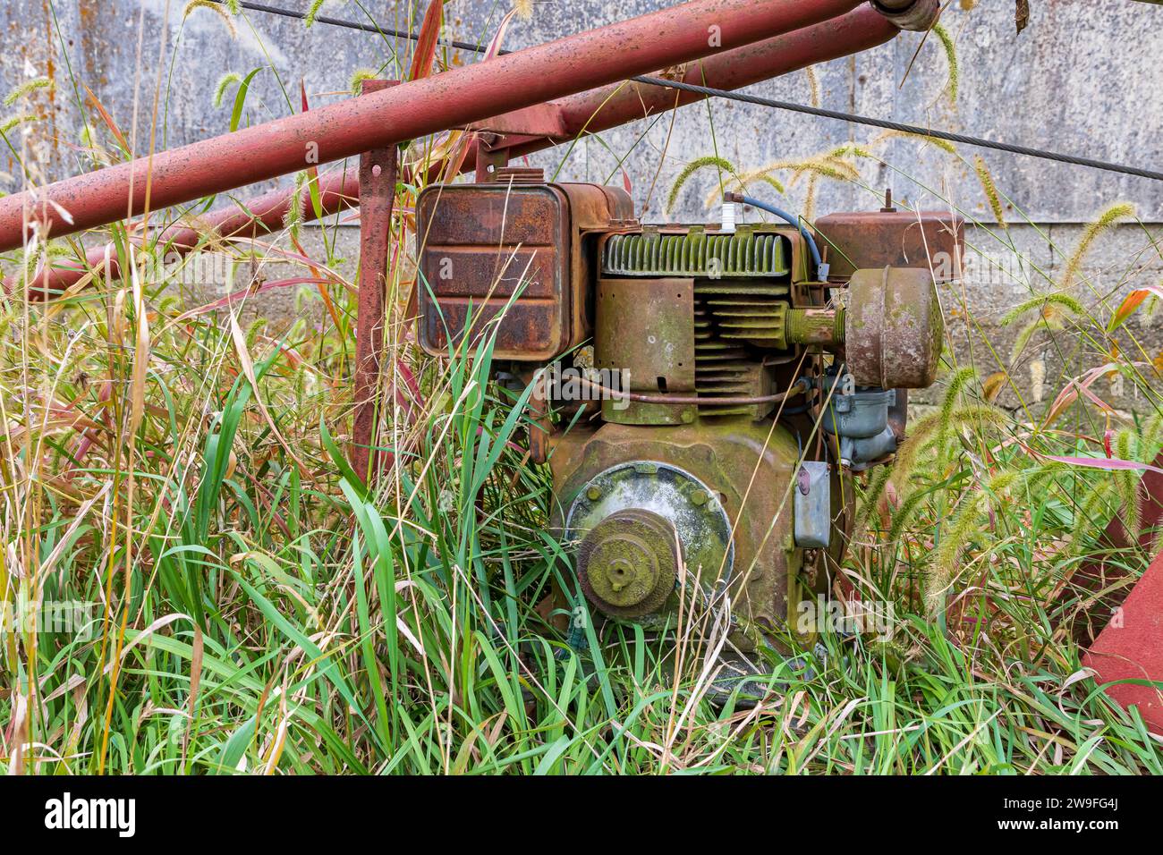 Alte, rostige Farmschnecke, die hinter der Scheune steht. Konzept für Entsorgung, Recycling, Lagerung und Schrott von Landmaschinen. Stockfoto