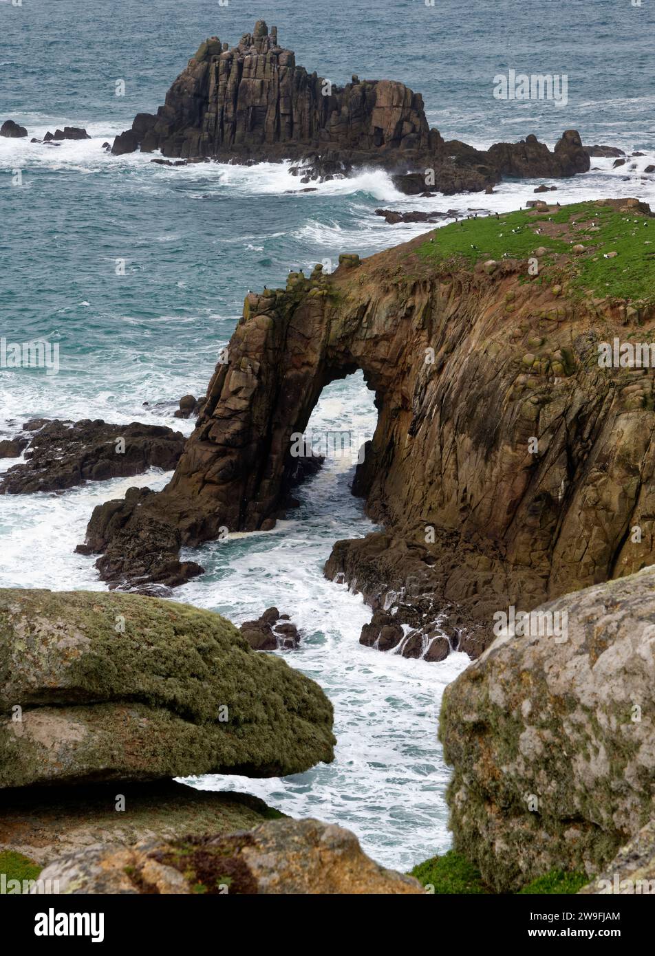 Rock Arch of Enys Dodnan mit Armed Knight Rocks dahinter, Zawn Wells, Land's End, Cornwall, Großbritannien Stockfoto