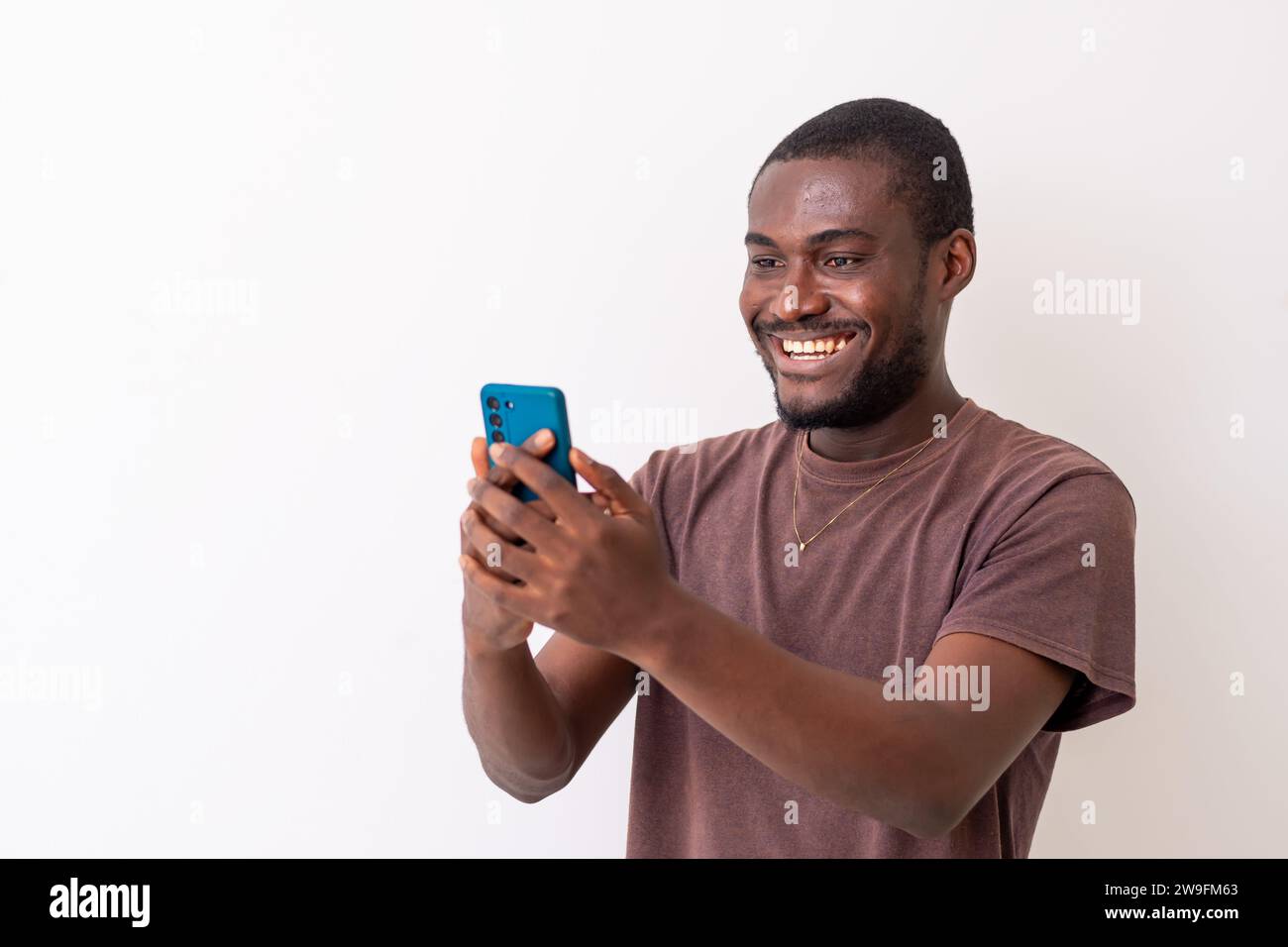 Überglücklich afrikanischer schwarzer Mann, der sich auf das Handy freut, gute Nachrichten zu lesen. Afrikanischer Mann mit Smartphone, um Sportwetten online zu wetten. T Stockfoto
