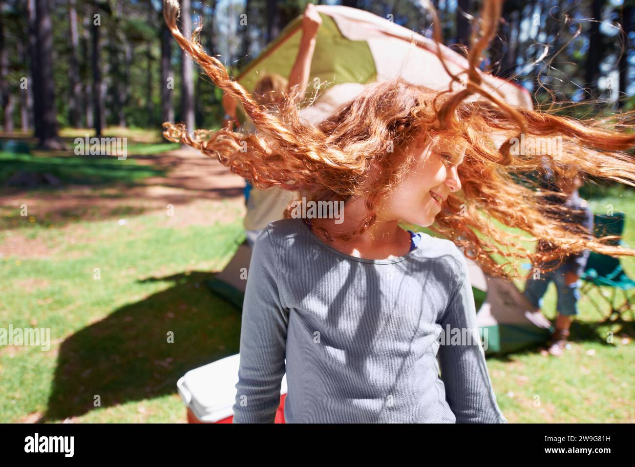 Fröhliches Mädchen, tanzen oder zelten im Park, um die Freiheit in einem lustigen Urlaub im Freien im Sommer zu feiern. Wald, verspielte oder aufgeregte Kinder mit Lächeln Stockfoto