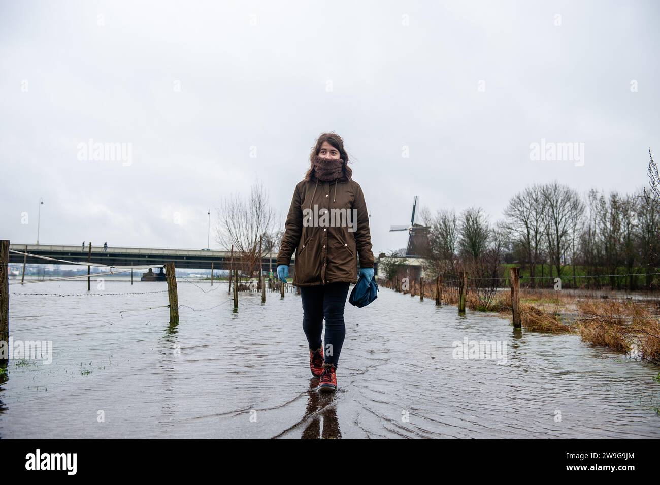 Deventer, Niederlande. Dezember 2023. Eine Frau wird über eine überflutete Straße laufen gesehen. Aufgrund des steigenden Wassers in der IJssel stellt die Gemeinde Deventer Sandsäcke an den Kai, um die Altstadt zu schützen. Der starke Regen, der in den letzten Monaten gefallen ist, kombiniert mit der Tatsache, dass die Alpen für diese Jahreszeit ungewöhnlich warm sind, hat die IJssel in Overijssel, Gelderland, Drenthe, Brabant und Limburg überschwemmt. (Foto: Ana Fernandez/SOPA Images/SIPA USA) Credit: SIPA USA/Alamy Live News Stockfoto