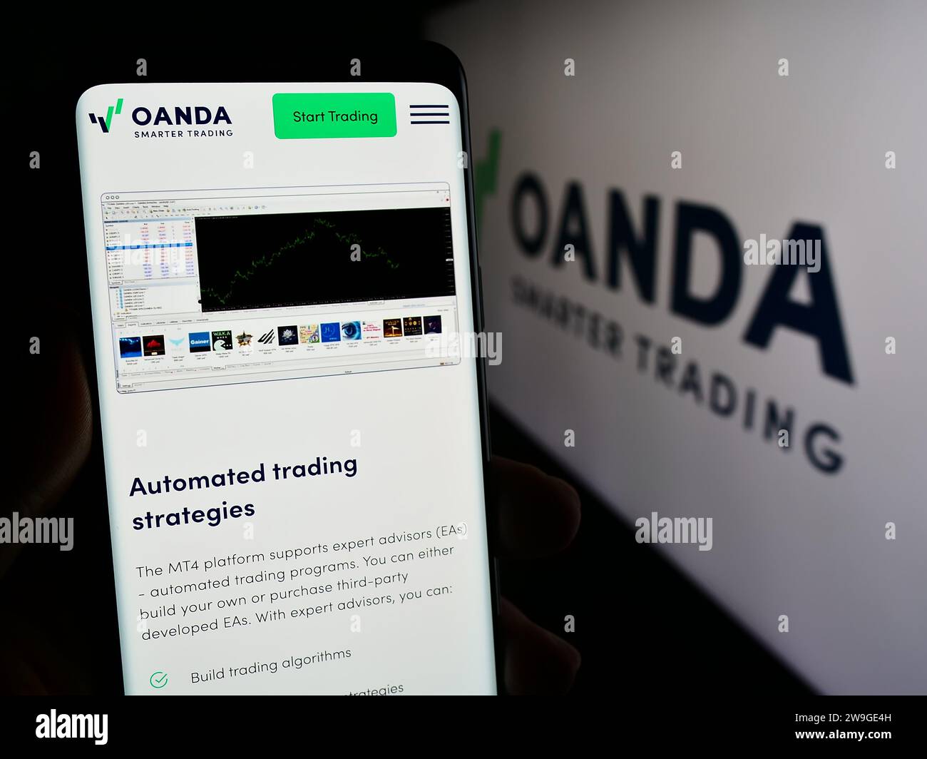 Person, die ein Mobiltelefon mit einer Webseite des US-amerikanischen Unternehmens OANDA Business Information Services Inc. Mit Logo hält. Konzentrieren Sie sich auf die Mitte des Telefondisplays. Stockfoto