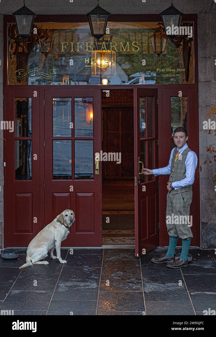 Junger Hotelportier öffnet die Tür im The Fife Arms Hotel in Breamer, Aberdeenshire, Schottland. Stockfoto