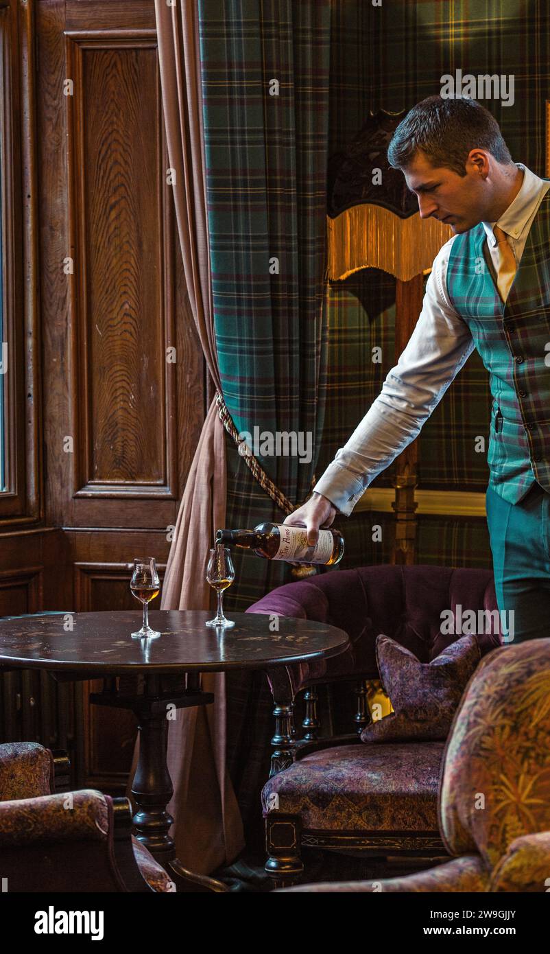 Der Kellner gießt Single Malt Whisky aus einer Flasche in das Glas auf dem Tisch. Stockfoto