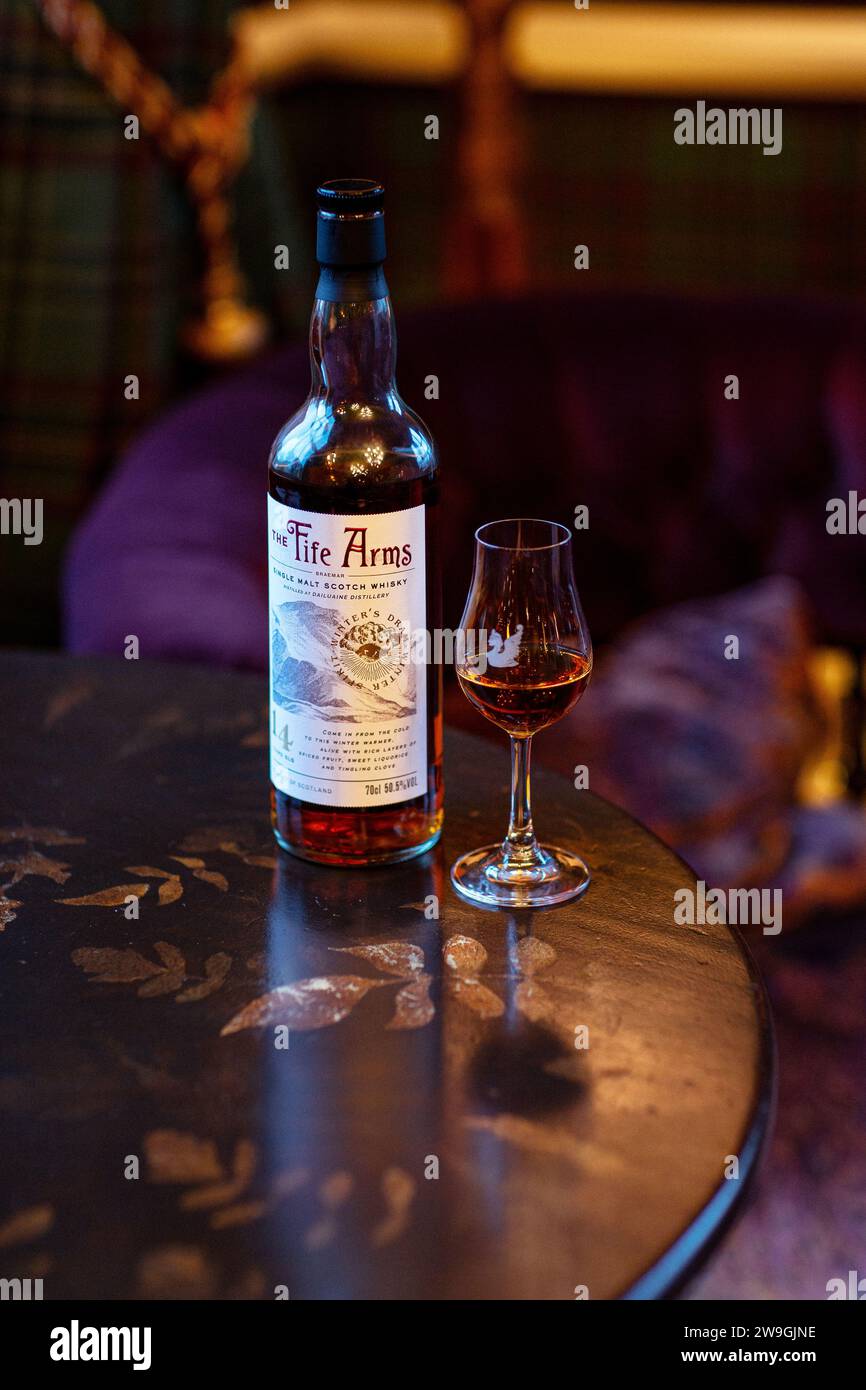 Single Malt Whisky Flasche mit Glas Whiskey und gemütlichem Wohnzimmer Hintergrund. Stockfoto