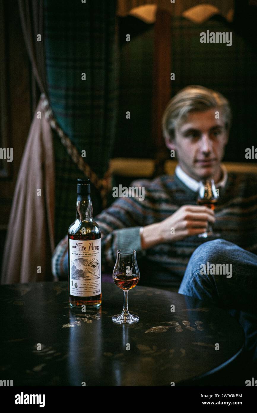 Single Malt Whiskyflasche mit jungen Männern, die Whisky trinken Stockfoto