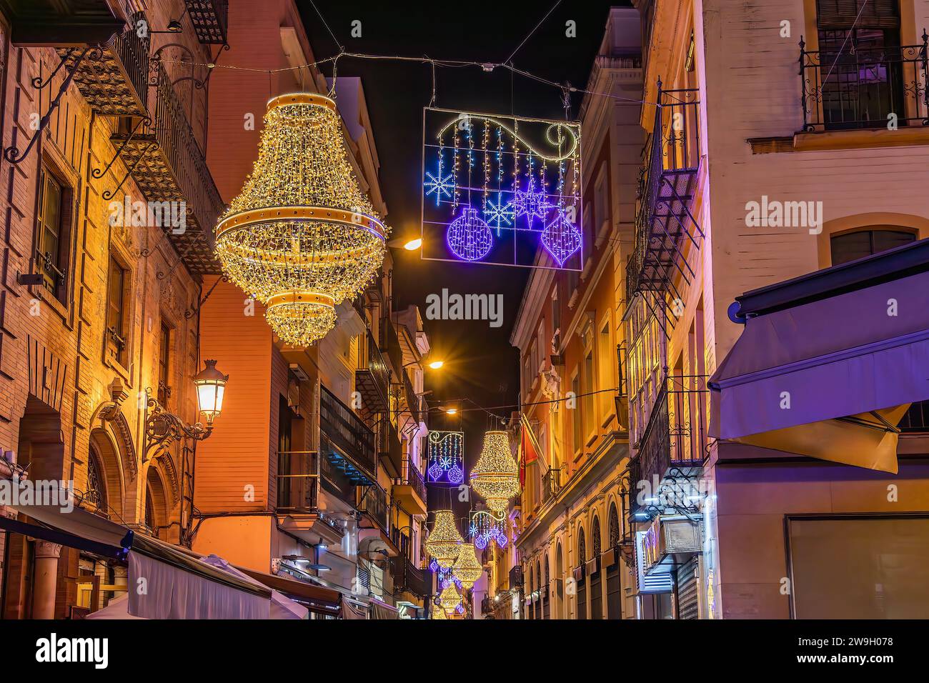 Sevilla, Spanien - 16. Dezember 2023: Weihnachtsbeleuchtung in der Sierpes Street in Form eines goldenen Kristallleuchters im Empire-Stil in Sevilla Stockfoto