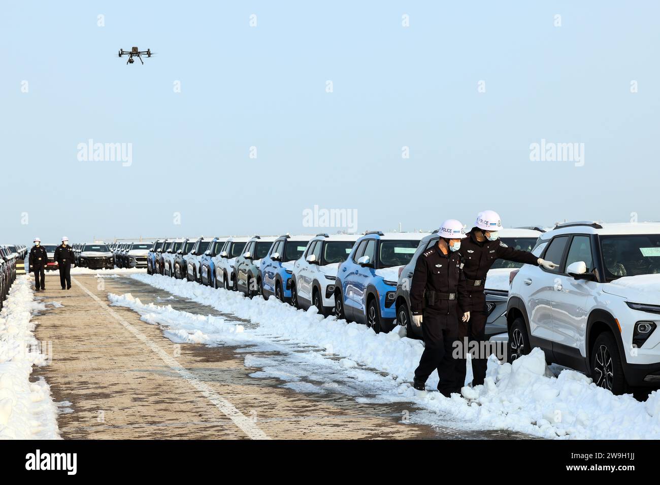 (231228) -- YANTAI, 28. Dezember 2023 (Xinhua) -- Polizeibeamte überprüfen Fahrzeuge, die für den Export im Hafen Yantai in der ostchinesischen Provinz Shangdong geladen werden, 27. Dezember 2023. Yantai Port ist Chinas Nutzfahrzeuglogistik-Basis und ein zentraler Logistikhafen für Nutzfahrzeuge in Nordchina. Yantai Port hat sein Geschäft in die integrierte Lieferkette der globalen Nutzfahrzeugindustrie eingebettet und einen ungehinderten globalen Logistikkanal für Nutzfahrzeuge von Yantai nach Nordamerika, Afrika, Europa, dem Nahen Osten und anderen Regionen eröffnet. Sie hat auch die grenzüberschreitende se ins Leben gerufen Stockfoto