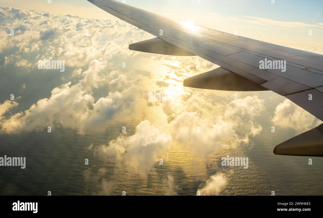 Flugzeugflügel, Wolken Schatten auf Wasser. Schatten einer Wolke auf dem Wasser Meer, Flugzeugfenster Blick auf gewelltes Wasser mit Sonnenstrahlen, die durch Wolken leuchten Stockfoto