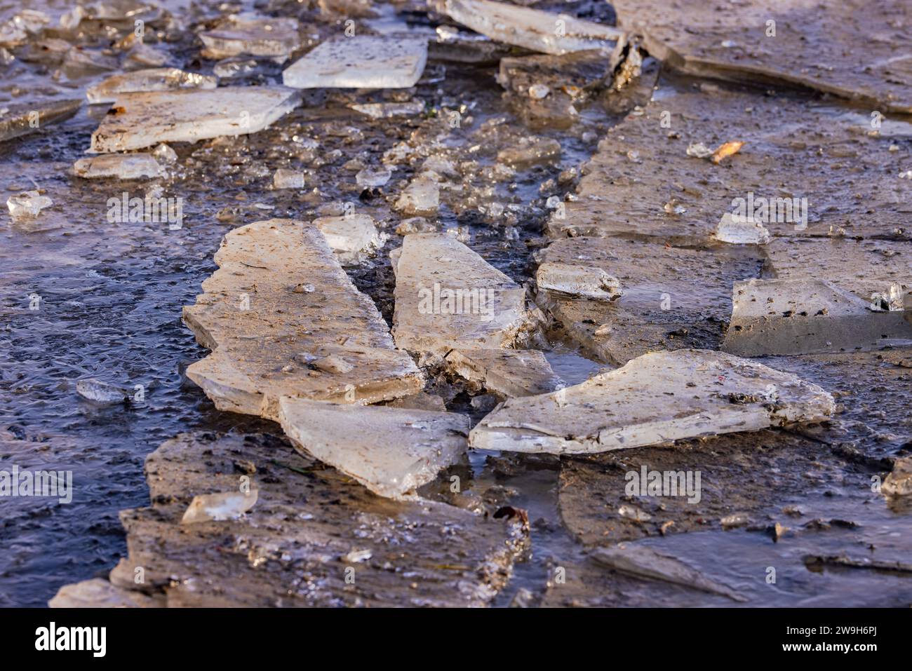Gefrorene Pfütze mit Eis und Eisfragmenten im Winter bei Sonnenschein Stockfoto