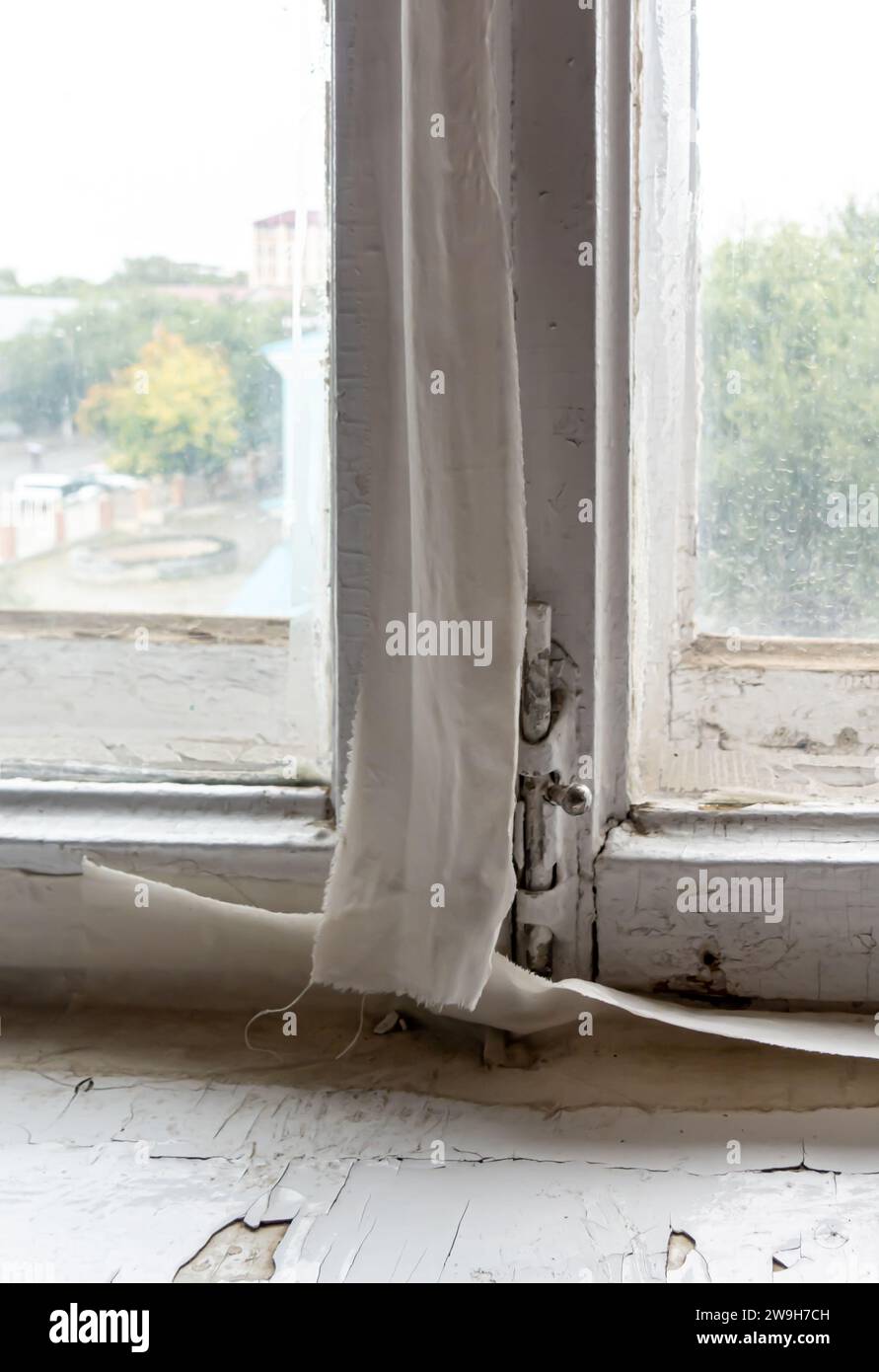 Eine aufgewärmte Nähte an einem Fenster im sowjetischen Stil. Ein Band, das an den Nähten zwischen einem Fensterrahmen und einer Fensterscheibe befestigt ist. Winterwärme, Aqtobe Stockfoto