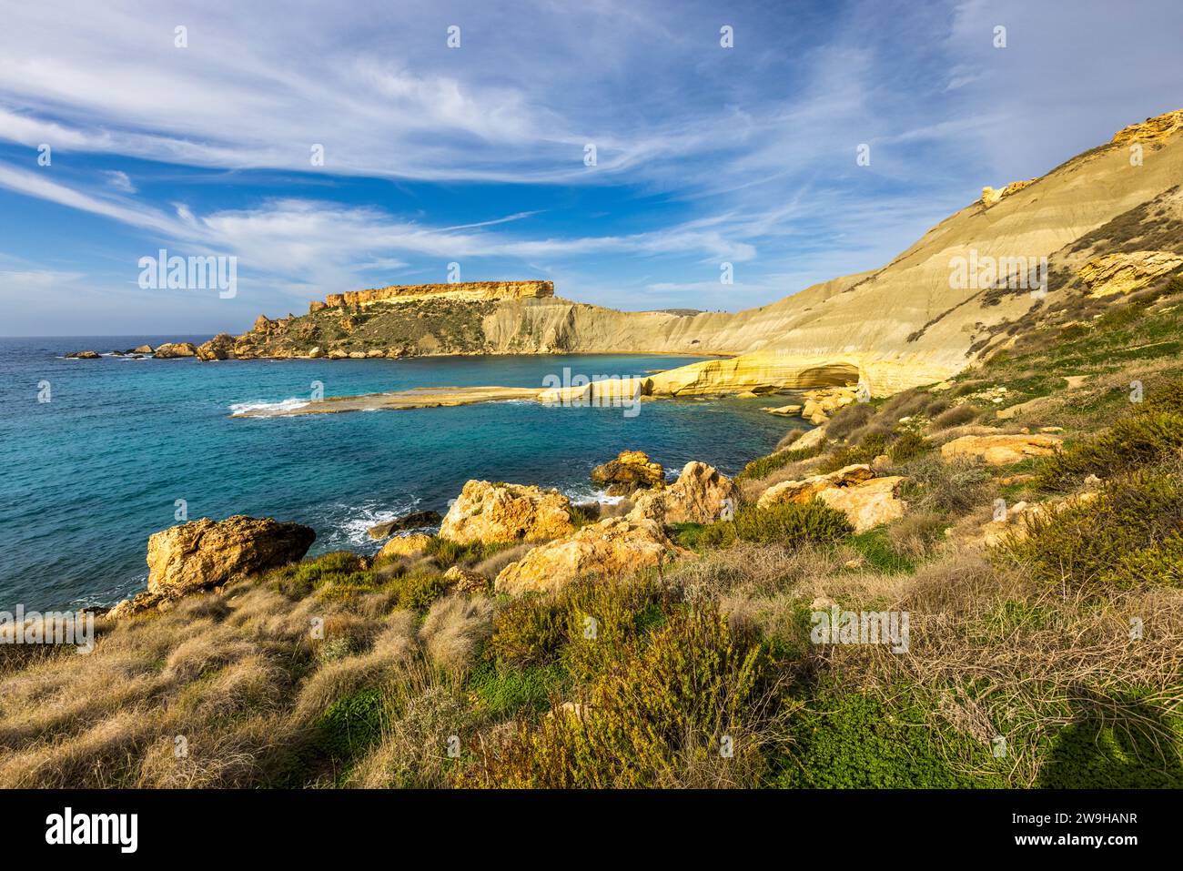 Għajn Tuffieħa-Bucht mit Il-Qarraba-Felsen. Strand mit dunklem Sand, beliebt zum Surfen und in einer Bucht, die von Hügeln umgeben ist, mit einem Küstenpfad in der Nähe von L-Imġarr, Malta Stockfoto