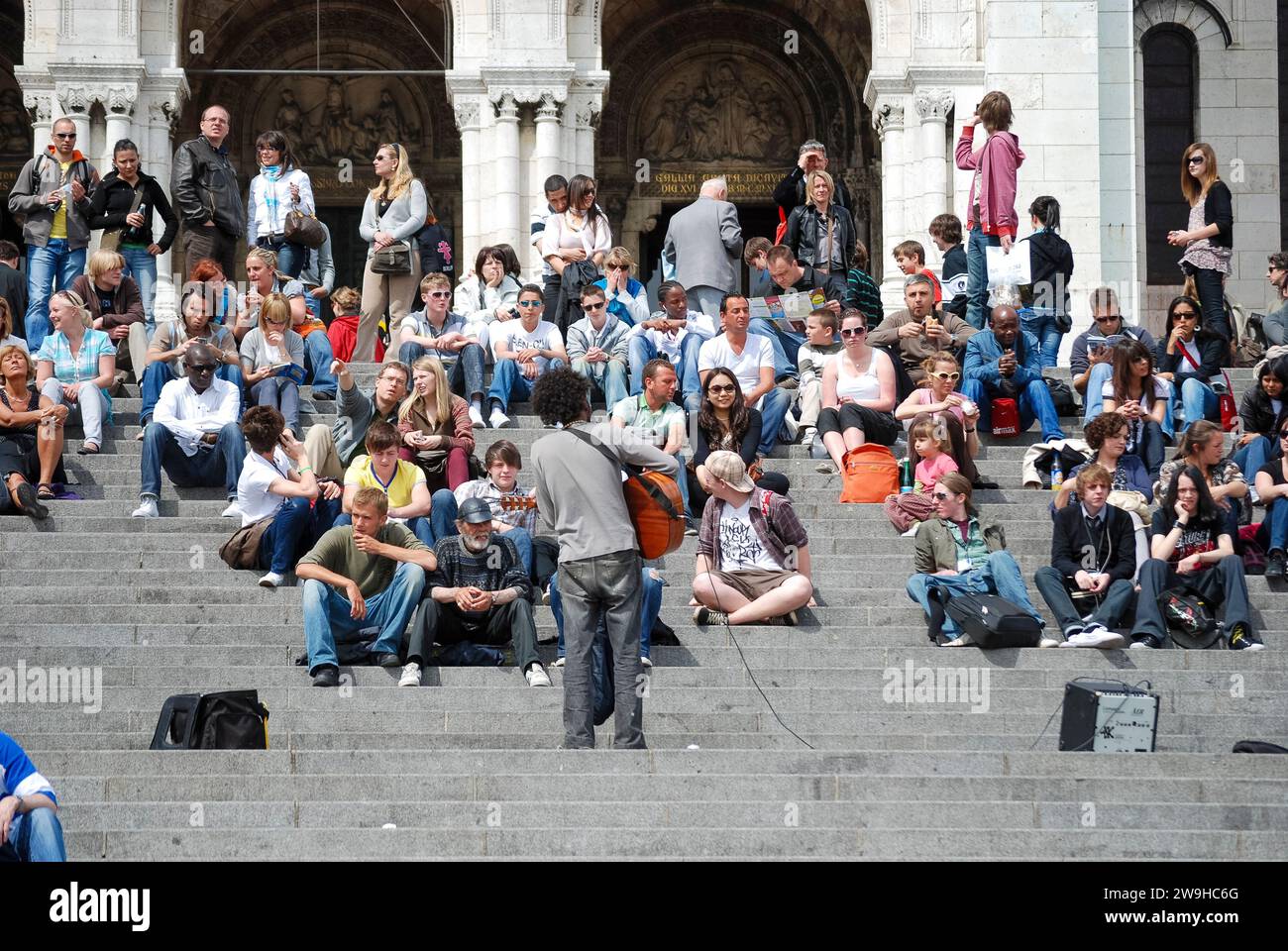 Busker, der vor einer Menge junge Menschen auf den Stufen der Basilika Sacré-Coeur (Heiliges Herz) in Paris, Frankreich, vorführt Stockfoto