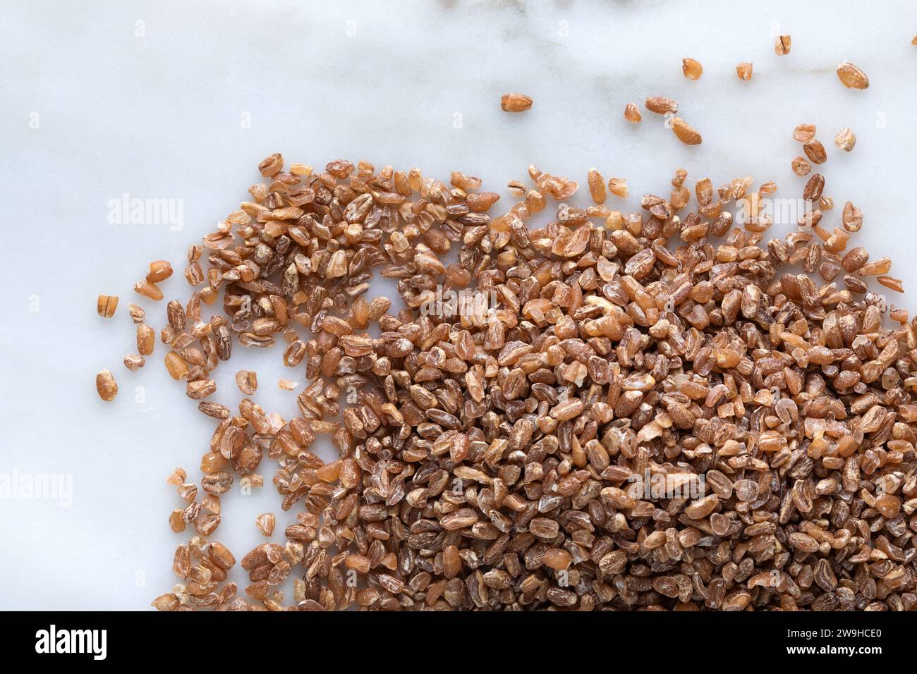 Nahaufnahme von Weizenkörnern auf weißem Marmorhintergrund. Gesundes Lebensmittelkonzept. Stockfoto