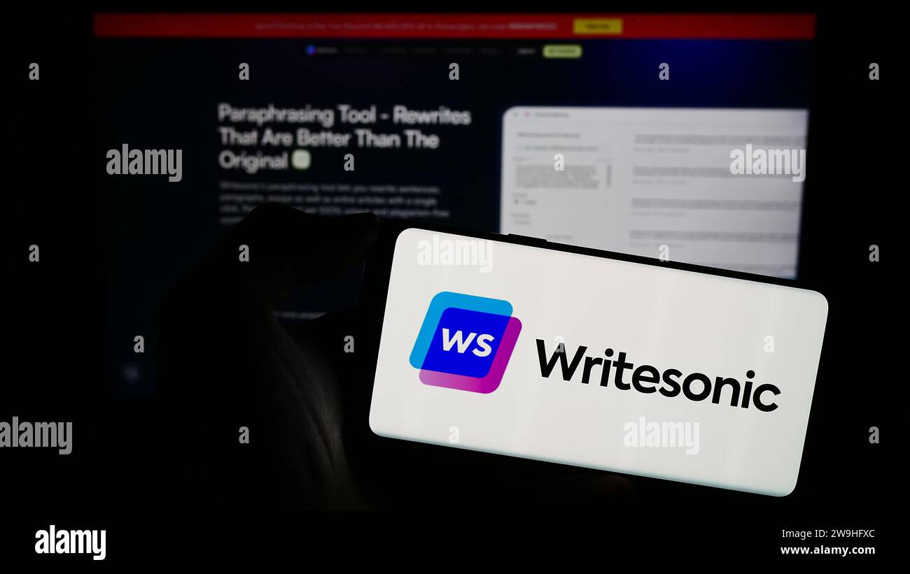 Person, die ein Mobiltelefon mit dem Logo des US-amerikanischen Unternehmens für künstliche Intelligenz Writesonic Inc. Vor der Unternehmenswebseite hält. Schwerpunkt auf dem Display des Telefons. Stockfoto
