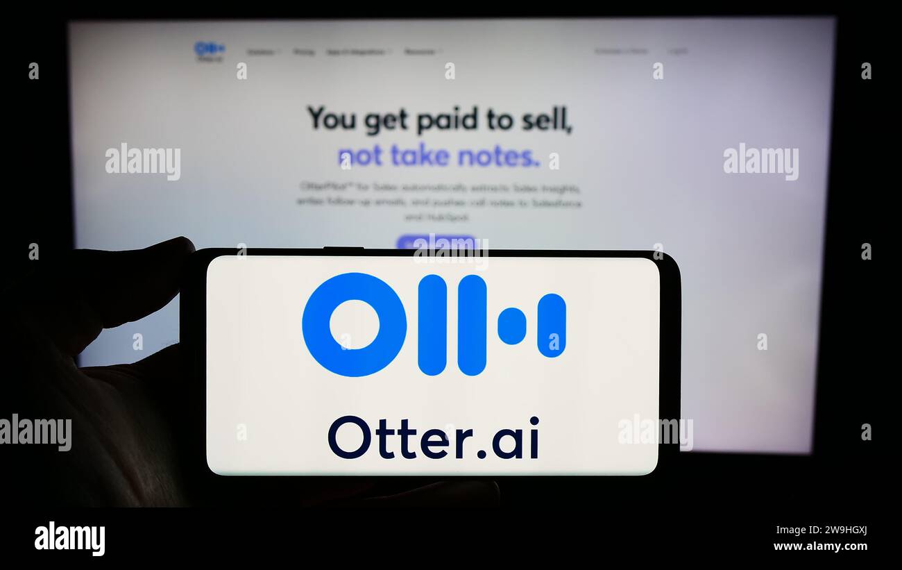 Person, die ein Smartphone mit dem Logo des US-amerikanischen Unternehmens für künstliche Intelligenz Otter.ai Inc. Vor der Website hält. Schwerpunkt auf dem Display des Telefons. Stockfoto