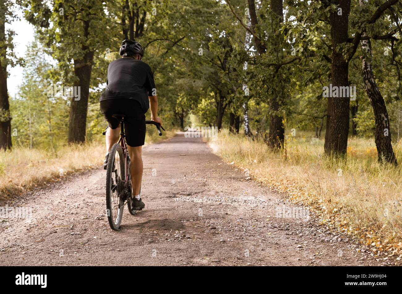 Radfahrer fahren auf einem Schotterrad entlang der Landstraße mit Gruben. Sport im Freien. Stockfoto