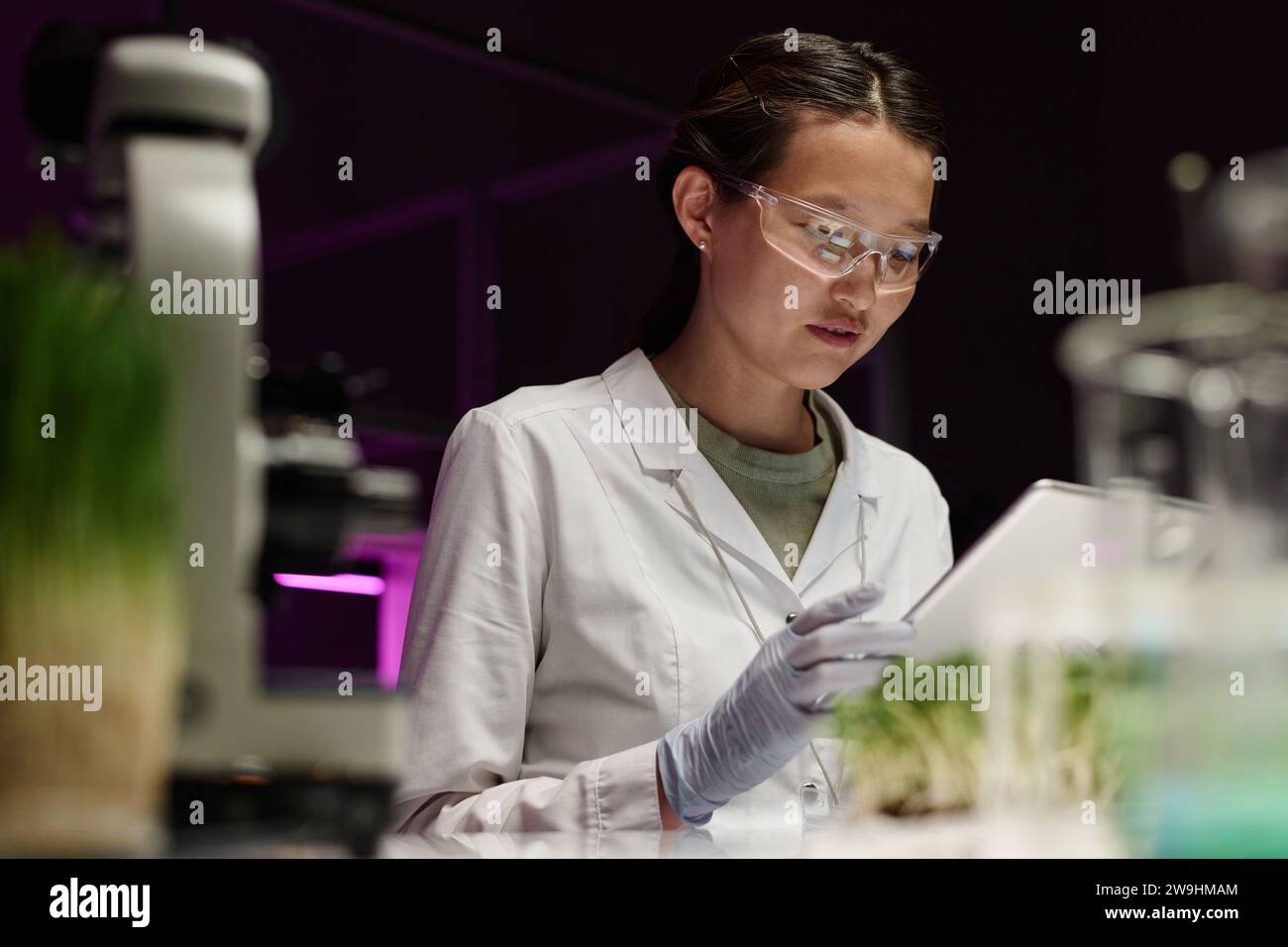 Junge asiatische Forscherin mit digitalem Tablet am Arbeitsplatz im Labor Stockfoto