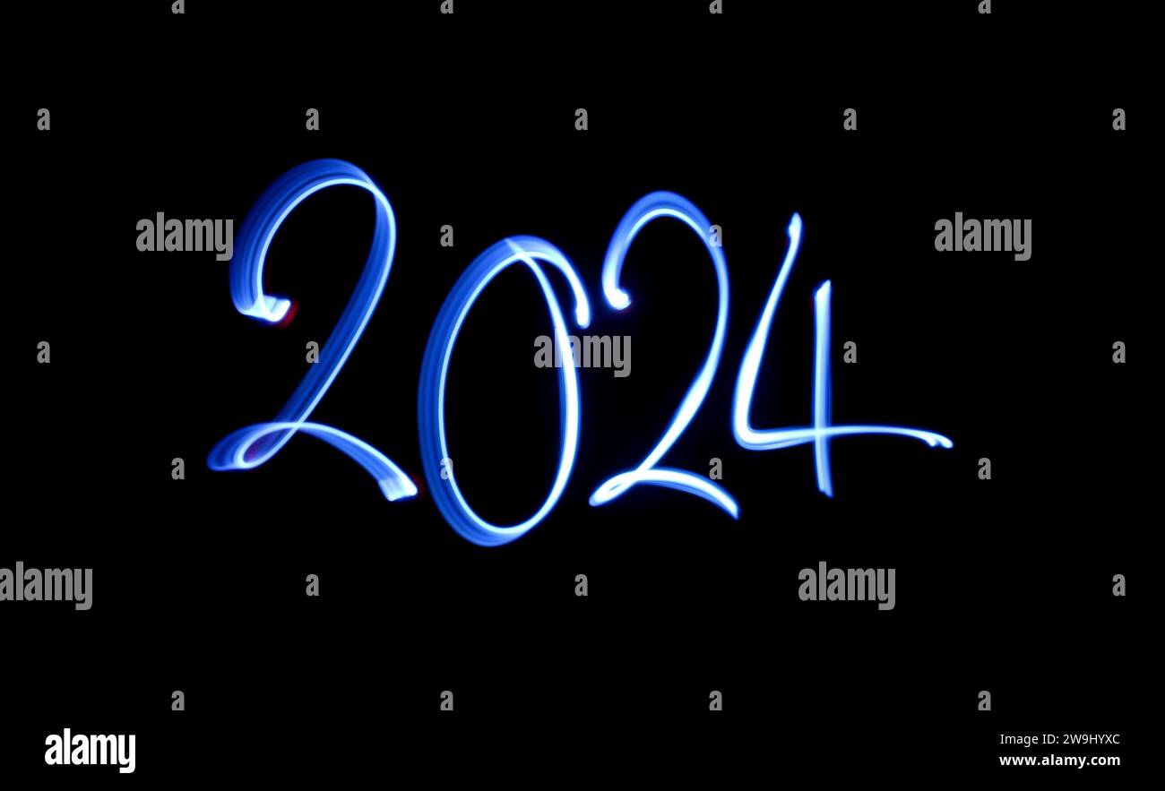 Ein Foto von „2024“ in leuchtendem blauem Licht auf einem Langzeitfoto vor schwarzem Hintergrund. Lichtmalerei Stockfoto