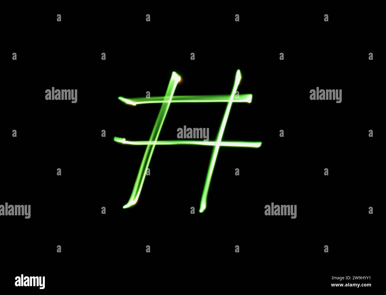 Ein Foto eines Hashtag-Symbols in leuchtendem grünem Licht in einem Langzeitfoto vor schwarzem Hintergrund. Lichtmalerei Stockfoto
