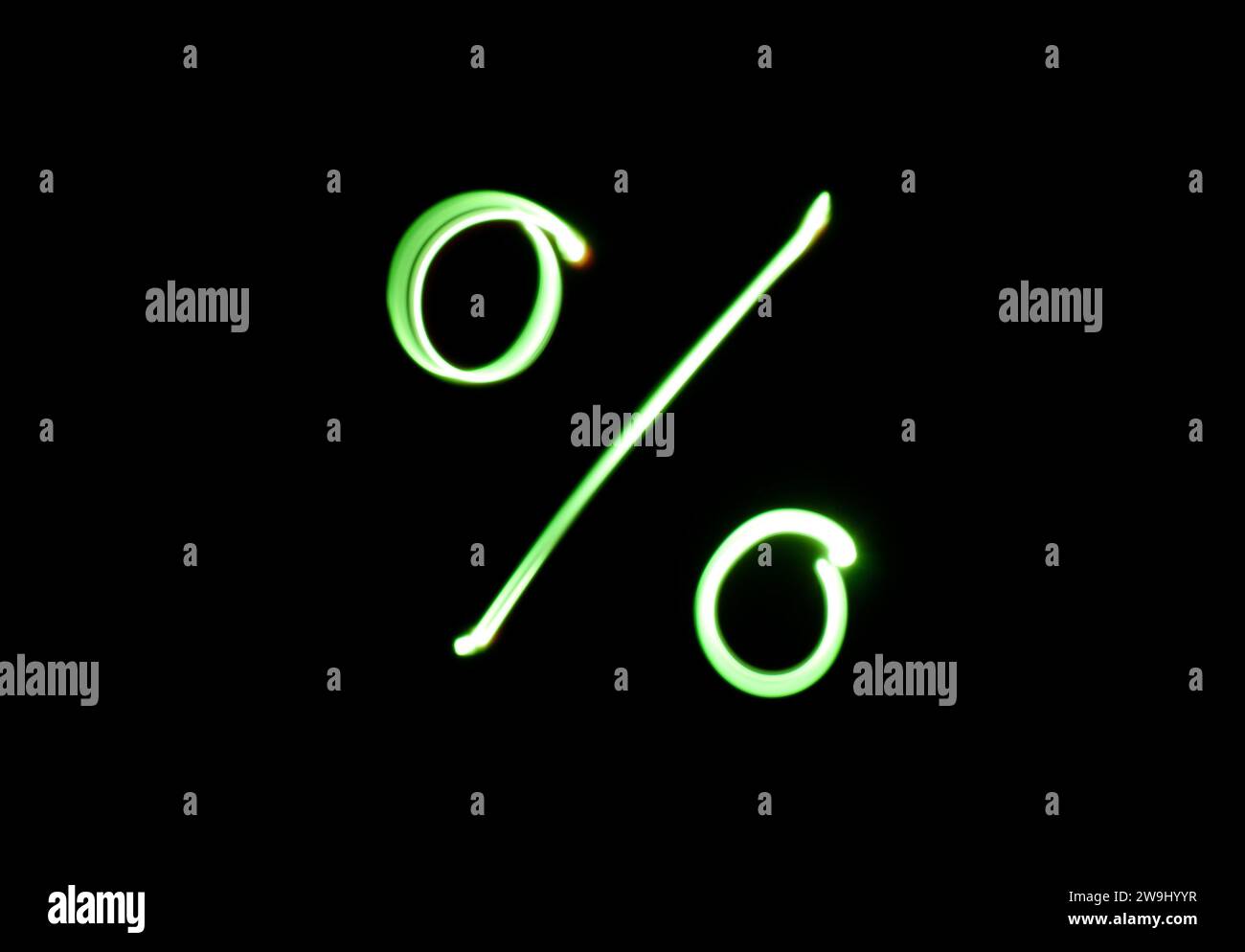 Ein Foto eines Prozentsymbols in leuchtendem grünem Licht auf einem Langzeitfoto vor schwarzem Hintergrund. Lichtmalerei Stockfoto