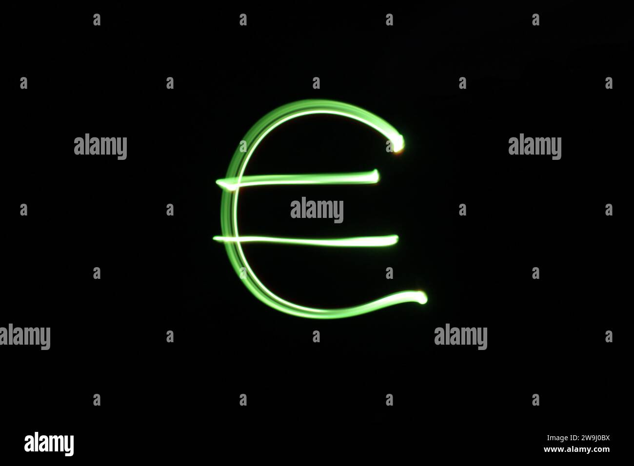 Ein Foto eines Euro-Währungssymbols in leuchtendem grünem Licht auf einem Langzeitfoto vor schwarzem Hintergrund. Lichtmalerei Stockfoto