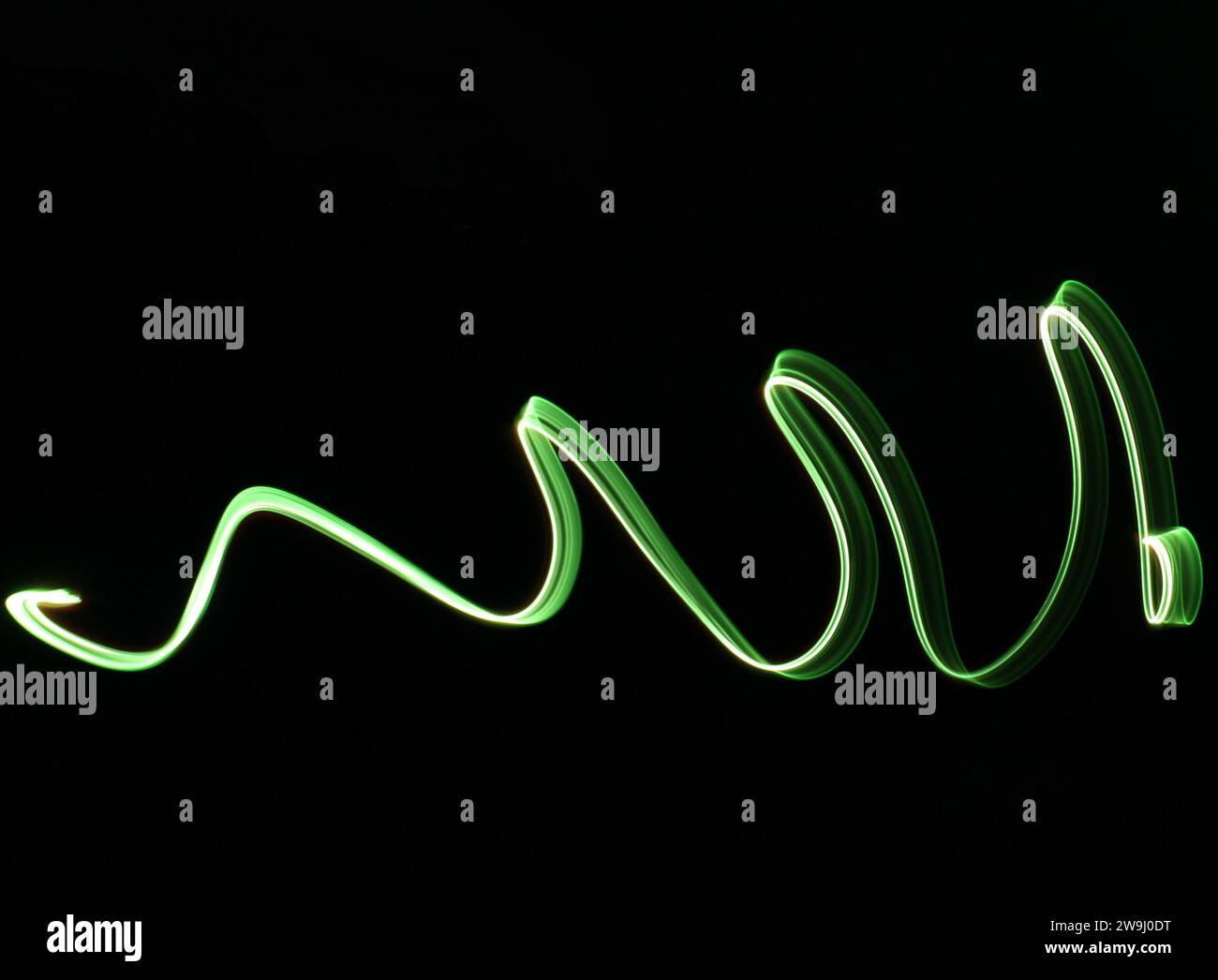 Ein Foto des Symbols in leuchtendem grünem Licht auf einem Langzeitfoto vor schwarzem Hintergrund. Lichtmalerei Stockfoto