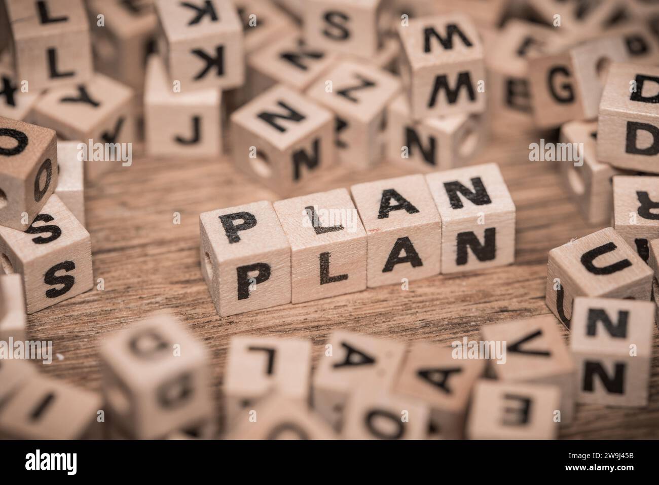 Plansymbol, Konzeptwort, Geschäftsidee für Entwicklung, Selbsterfüllungskonzept, verstreute Holzblöcke und bilden das Wort Plan Stockfoto