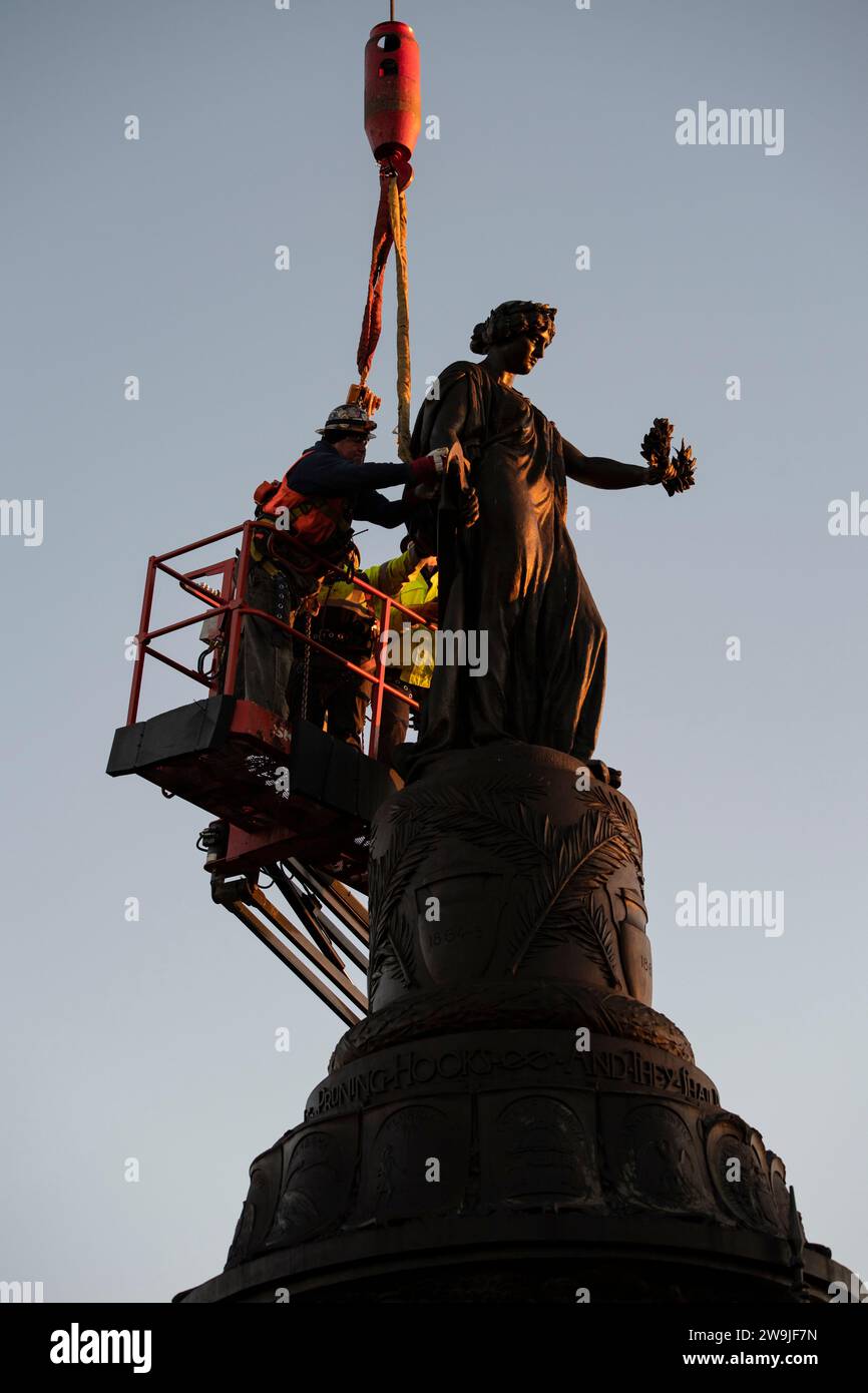 Arlington, Vereinigte Staaten von Amerika. Dezember 2023. Arbeiter befestigen Gurte an der Bronzestatue am Confederate Memorial in Section 16 des Arlington National Cemetery, bevor sie am 20. Dezember 2023 in Arlington, Virginia, mit einem Kran entfernt werden. Die Gedenkstätte zu Ehren von Mitgliedern der Konföderierten Staaten von Amerika wird in den New Market Battlefield State Historic Park verlegt. Kredit: Elizabeth Fraser/USA Army/Alamy Live News Stockfoto