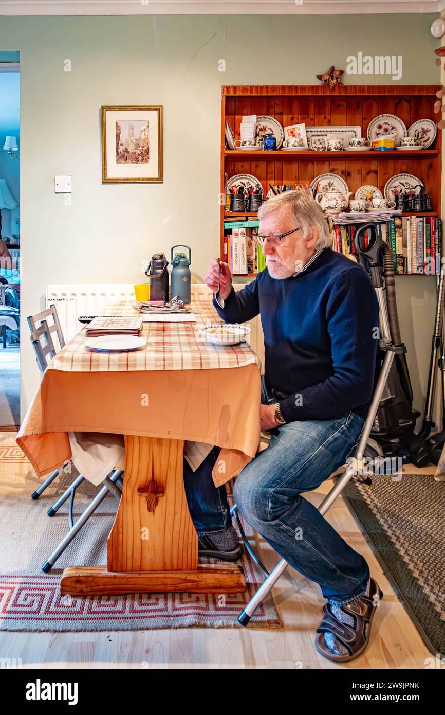 Ein Mann saß an einem Küchentisch und aß Frühstück Stockfoto