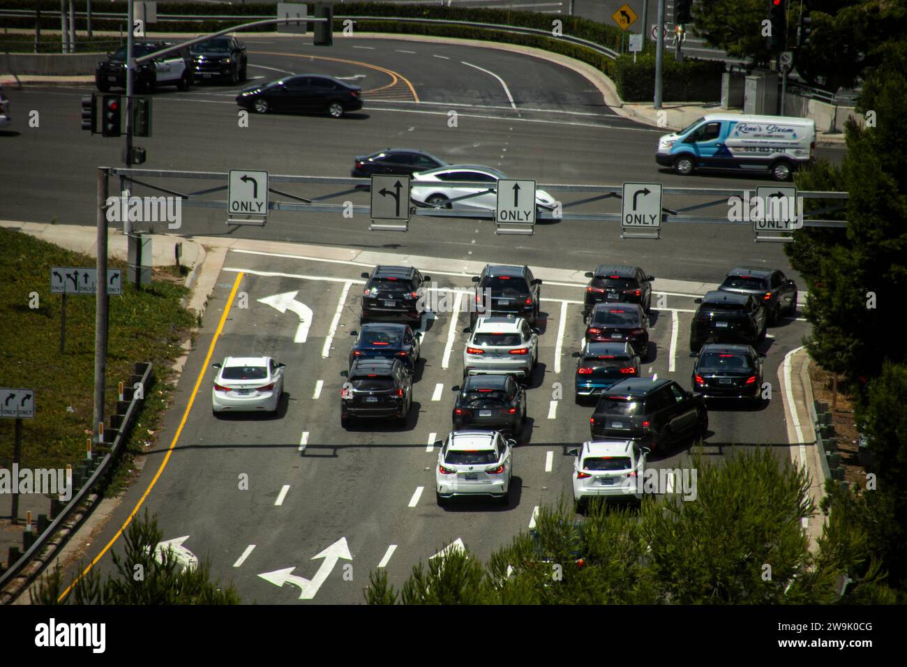 Der Verkehr wartet an einer roten Ampel an einer Kreuzung an Costa Mesa, CA. Beachten Sie die Pfeile zum Abbiegen nach links. Stockfoto