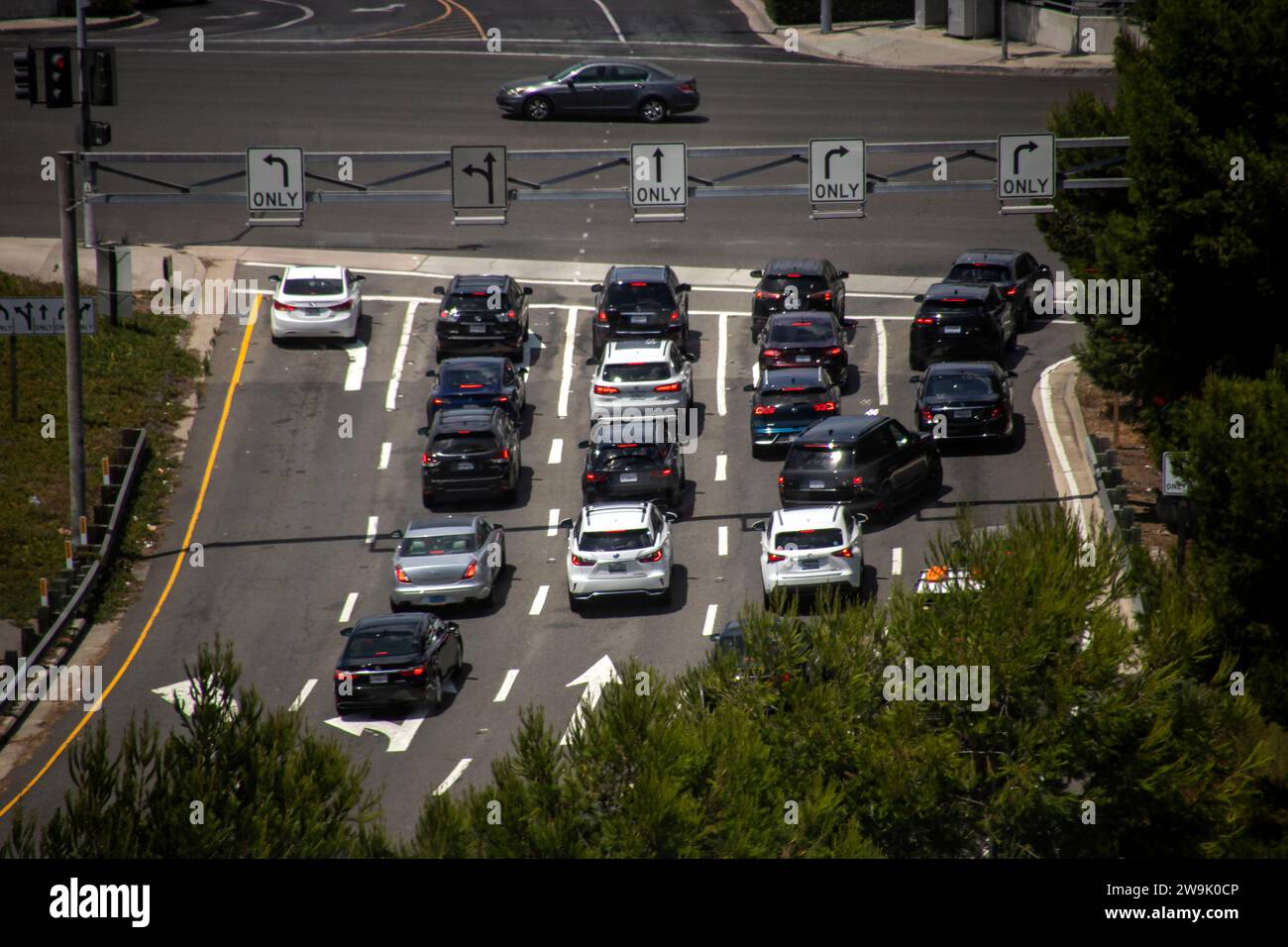 Der Verkehr wartet an einer roten Ampel an einer Kreuzung an Costa Mesa, CA. Beachten Sie die Pfeile zum Abbiegen nach links. Stockfoto