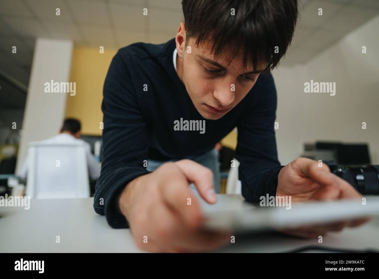 Gutaussehender junger Mitarbeiter sucht auf seinem Tablet nach Arbeit im Internet. Stockfoto