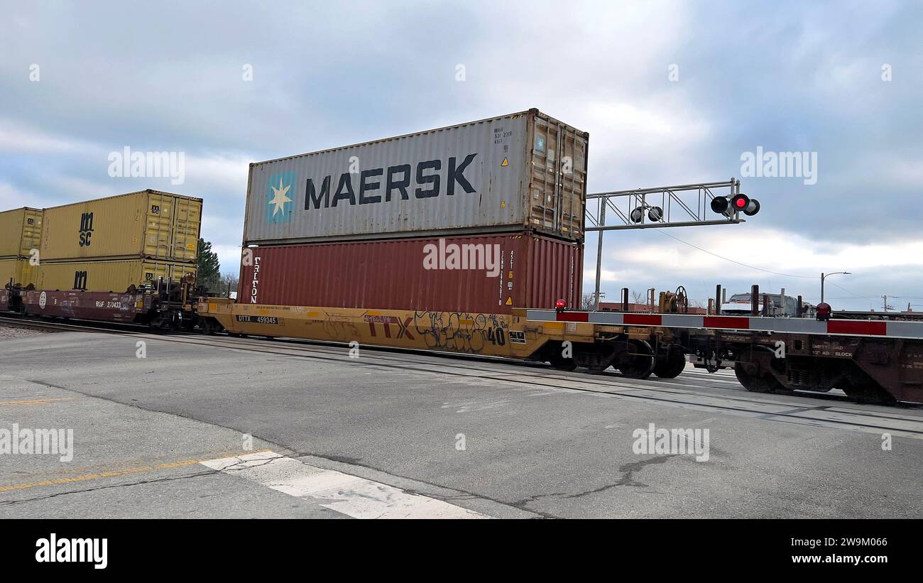 EMPORIA, KANSAS, USA - 28. DEZEMBER 2023 Ein Güterzug von Burlington Northern Santa Fe (BSNF), der eine sehr lange Reihe intermodaler Container zieht, darunter eine Nummer, die zur MAERSK-Reederei gehört und in westlicher Richtung zu den Westküstenhäfen Kaliforniens führt. Stockfoto
