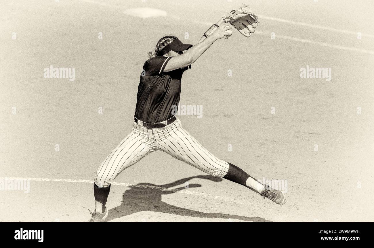 Ein weiblicher Softball-Spieler ist in Full Windup Pitching Antik Grainy Monochrom Stockfoto