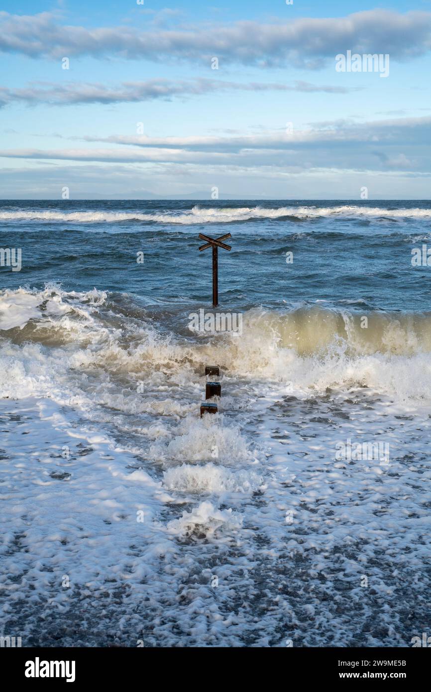 Seeverteidigungskühe und Wellen im windigen Meer am Findhorn Strand. Morayshire, Schottland Stockfoto