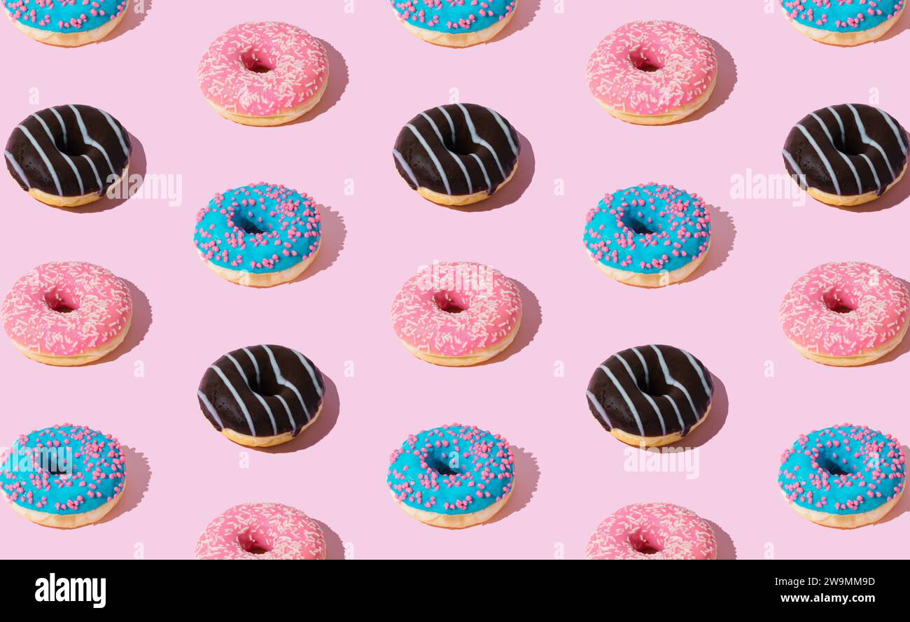 Kreatives Muster von bunten Donuts auf pastellrosa Hintergrund. Minimales Konzept. Trendiges Donuts-Muster. Leckere Essenszusammensetzung. Donuts-Ästhetik. Stockfoto